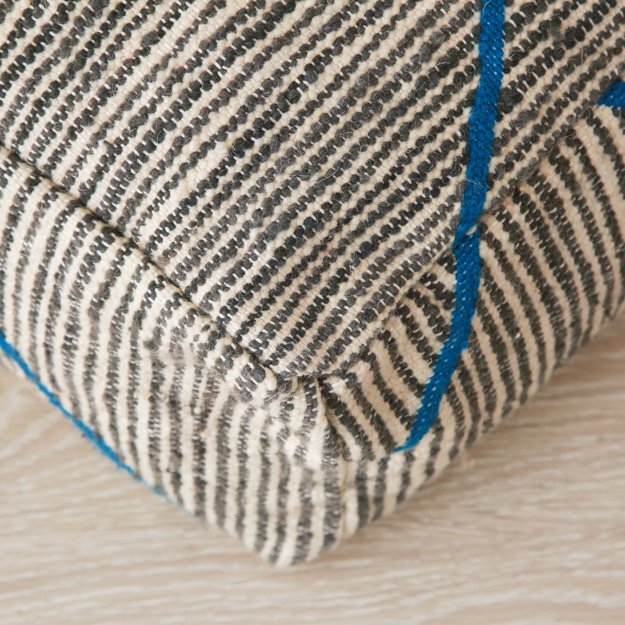 dettaglio dell'angolo di pouf zanafi bianco e grigio con righe blu