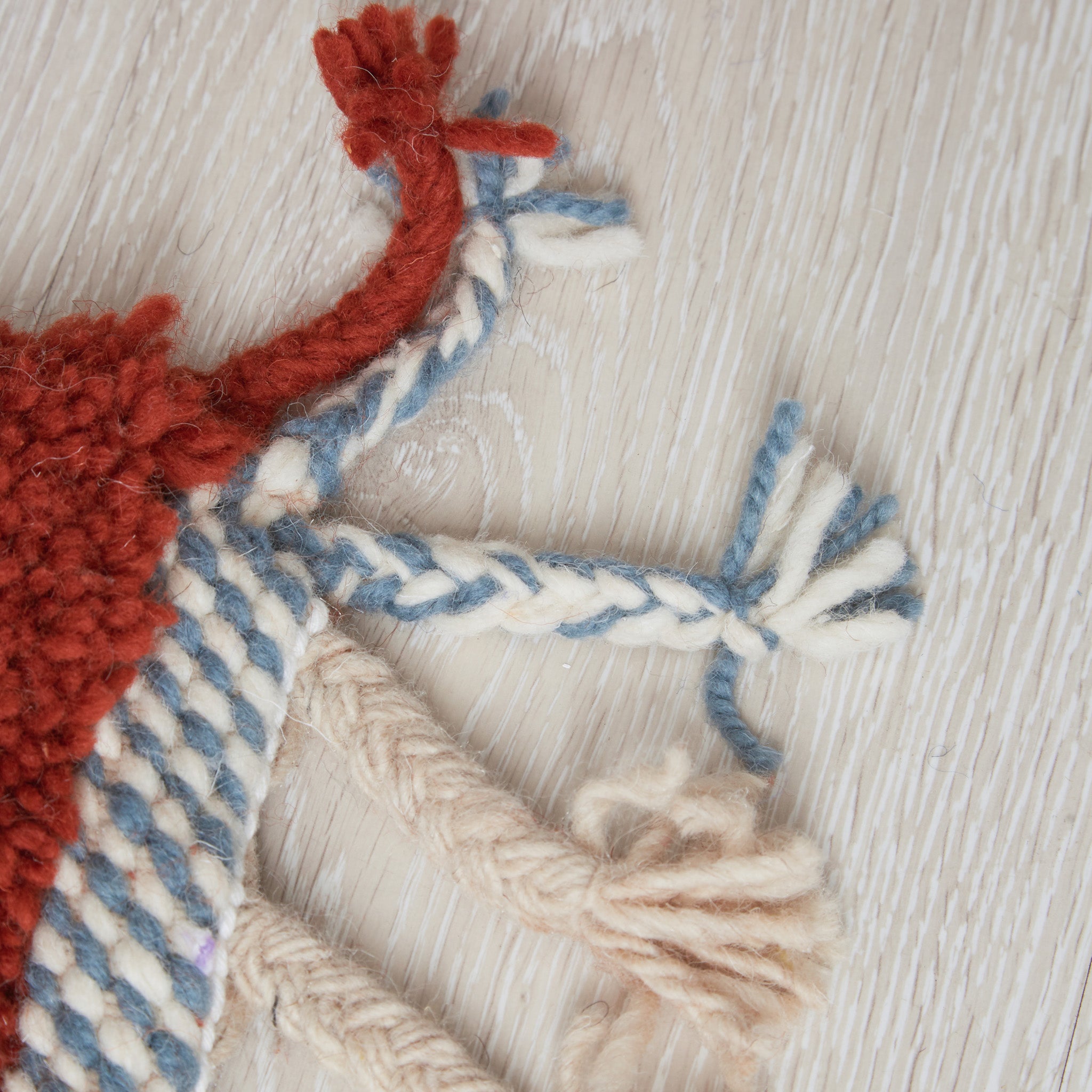 Dettaglio tappeto Animauì: nodi in lana  color terracotta e blu, frange intrecciate a mano, texture morbida della lavorazione artigianale marocchina
