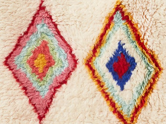 Dettaglio di tappeto bianco con decorazioni a rombi concentrici di più colori dai toni sgargianti e allegri