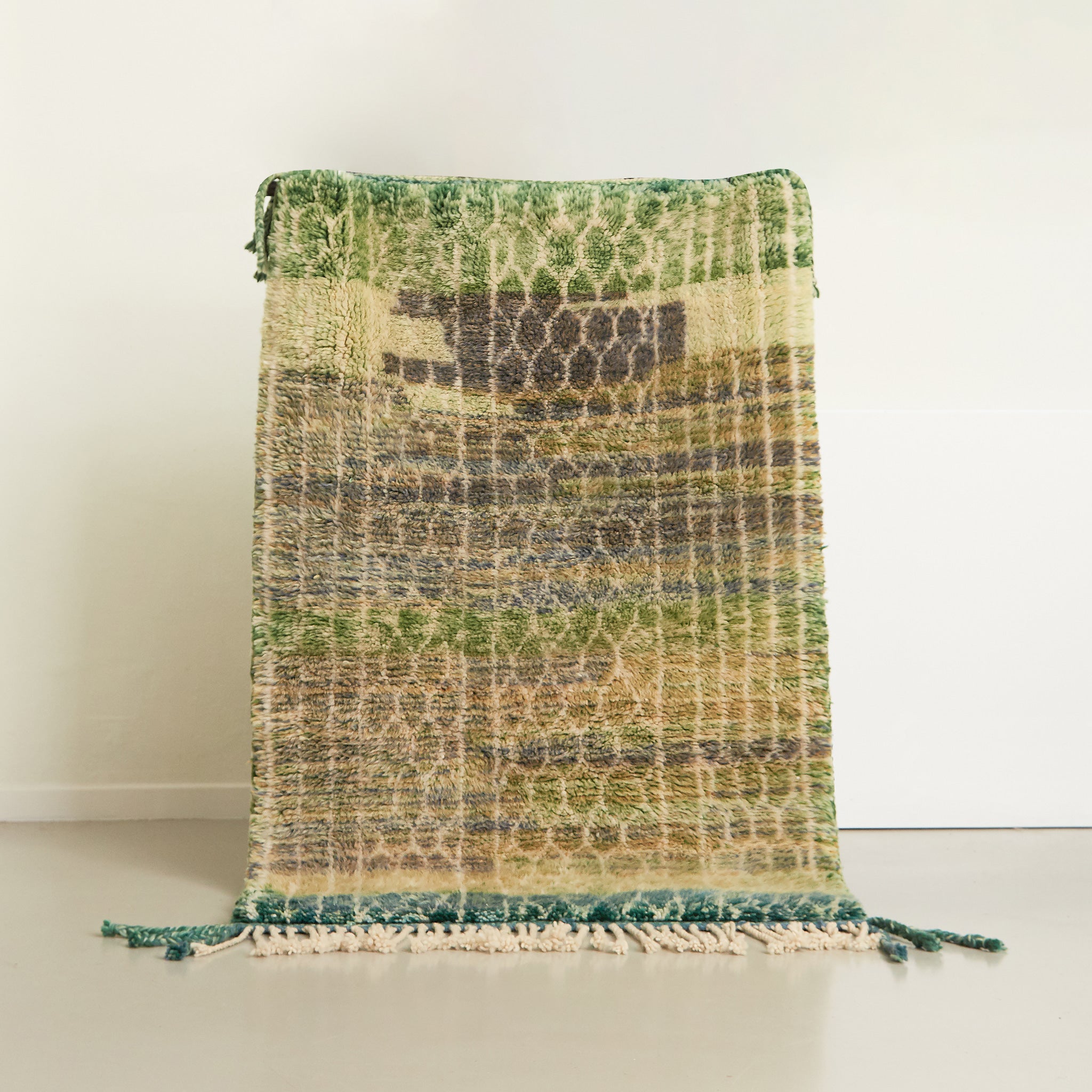 tappeto beni mrirt realizzato con morbida lana, la base del tappeto ha molte sfumature di verde e sono presenti delle linee bianche che formano un pattern creativo