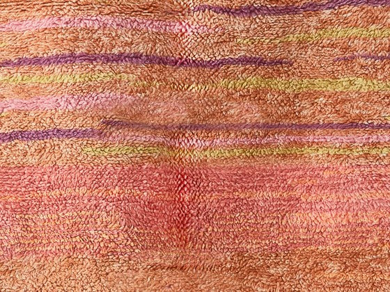 Dettaglio di tappeto sulle tinte del rosa, con linee orizzontali viola e gialle