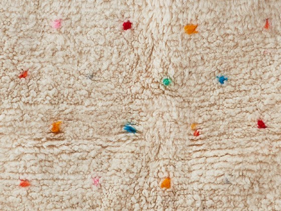 Dettaglio tappeto bianco costellato da puntini colorati