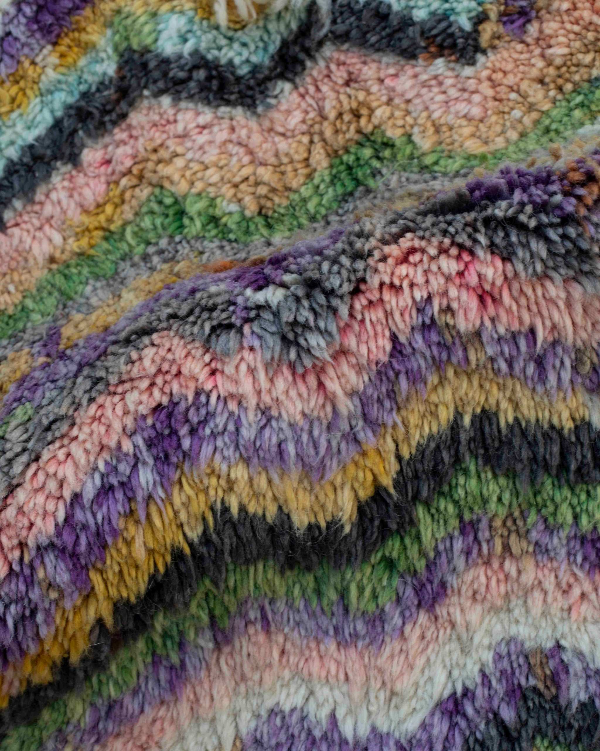 Primo piano texture tappeto Beni Ourain in lana annodata a mano, chevron ondulato multicolor con toni senape, verde, rosa e lilla, grigio scuro