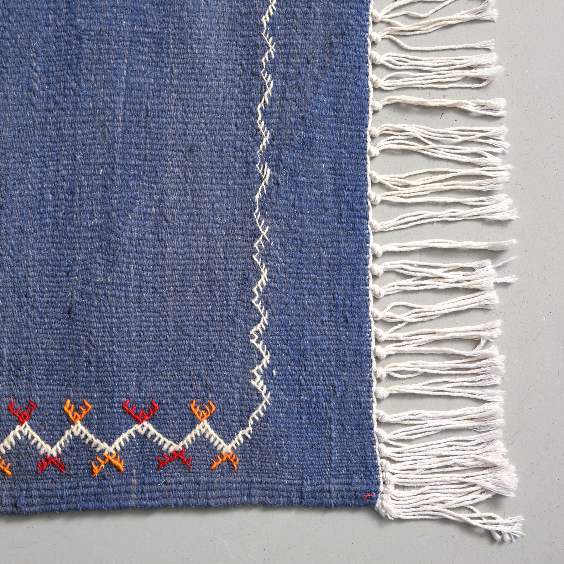 angolo e frangia di un tappeto marocchino berbero akhnif realizzato in lana blu, senza pelo
