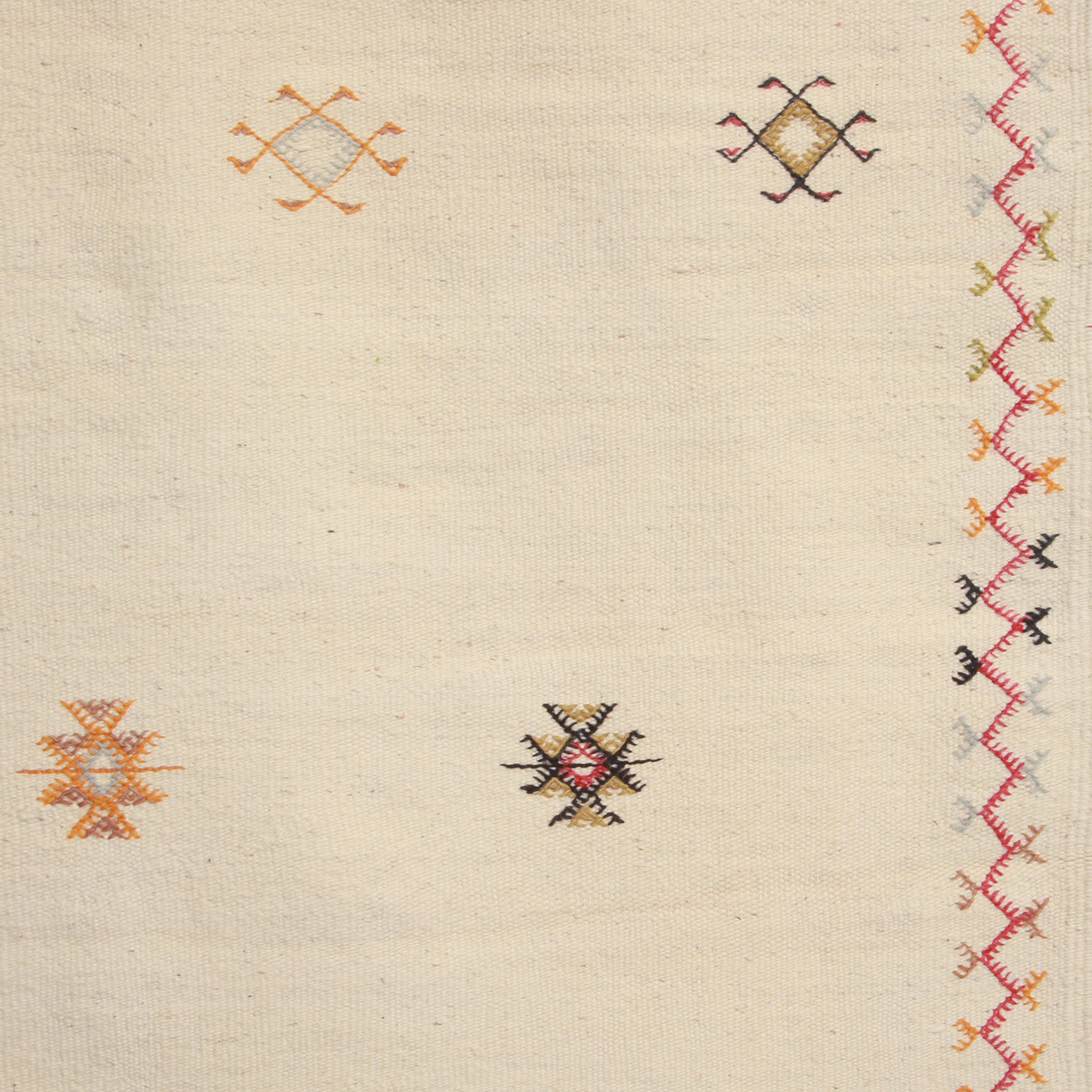 dettaglio della cornice e di quattro simboli amazigh ricamati su un tappeto marocchino akhnif a tessitura bianca in lana bianca