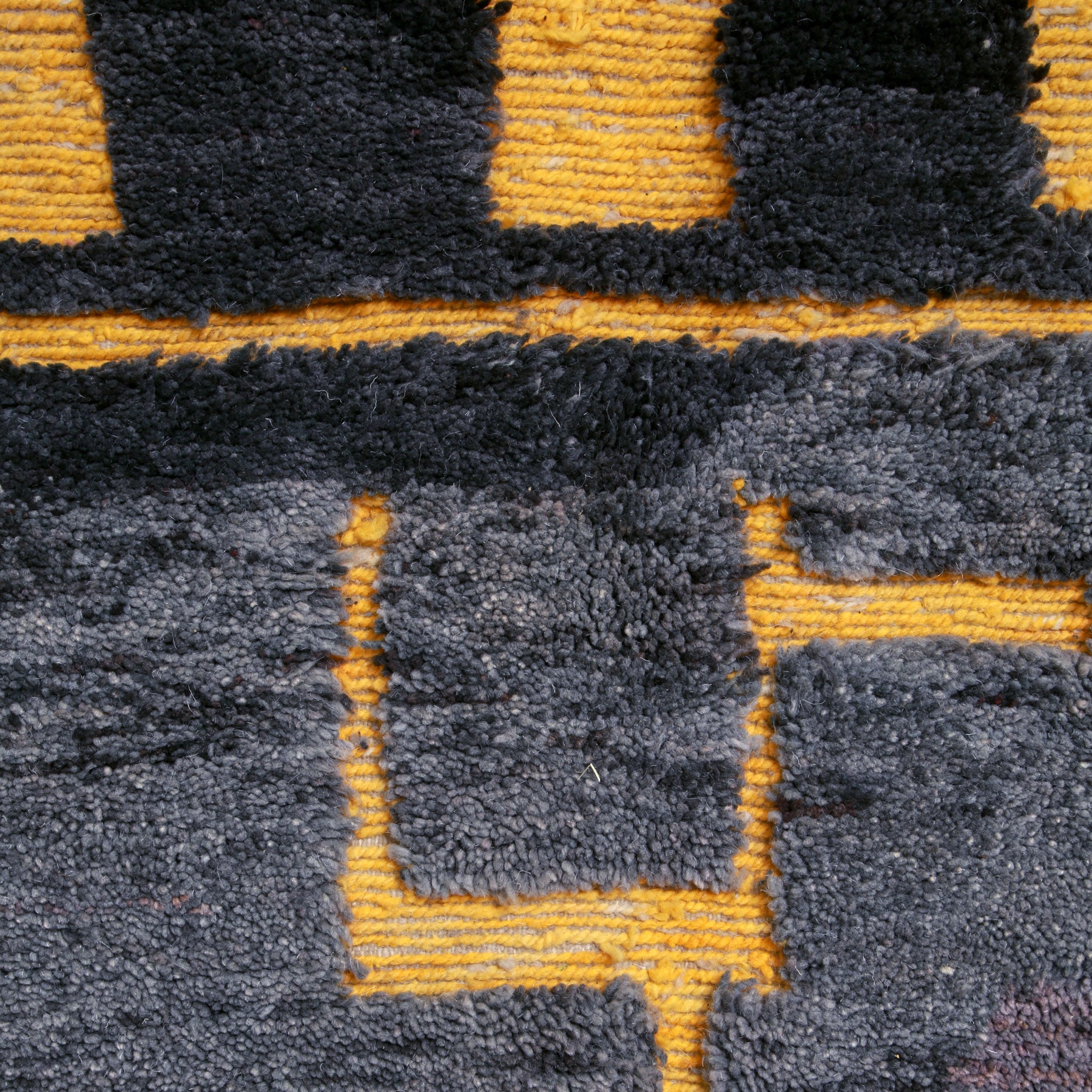 dettaglio della lana dalle sfumature di grigio con inserti in lana intrecciata gialla di un tappeto marocchino beni ourain realizzato a mano