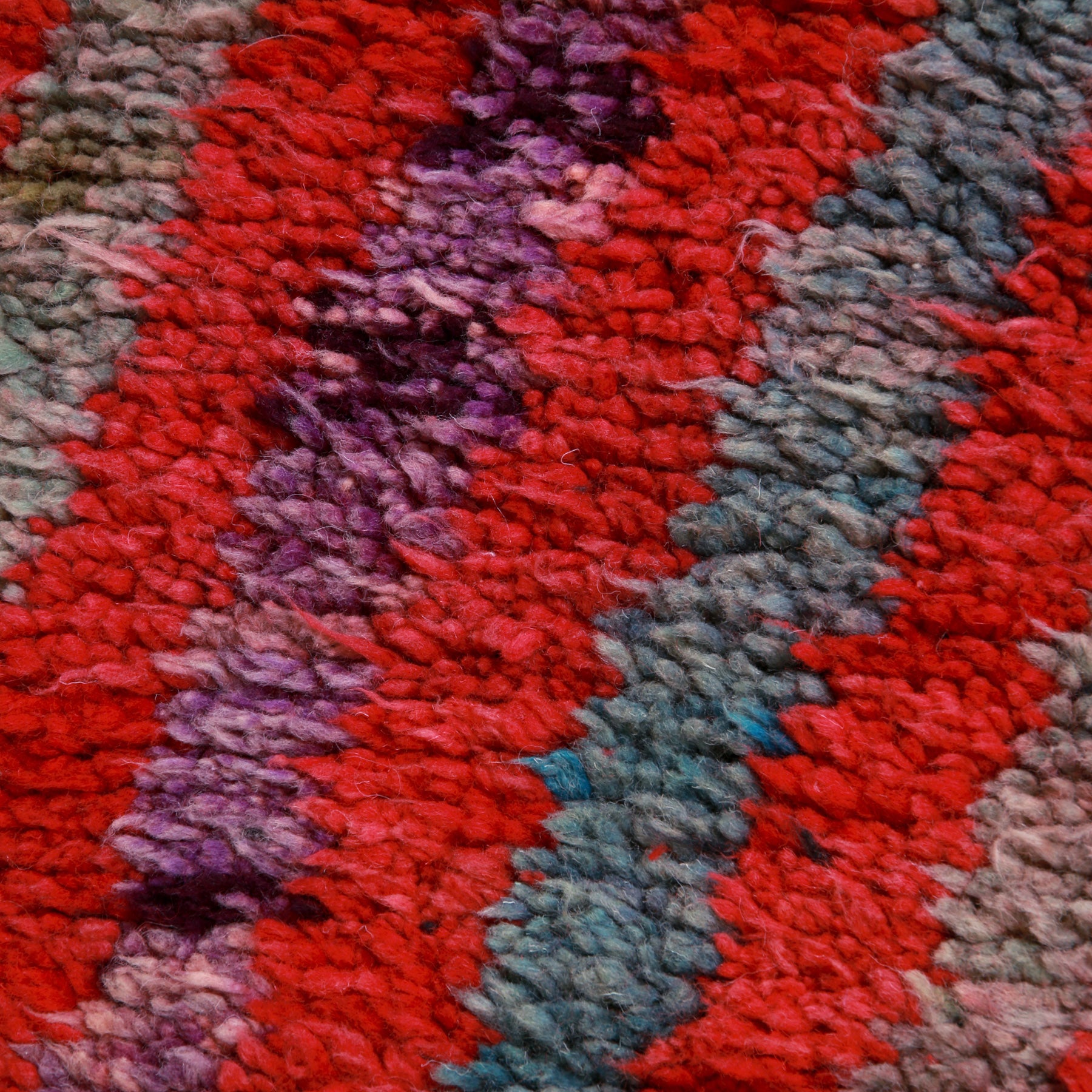 dettaglio dell'alternanza di righe rosse azzurro e viola di un tappeto boujaad