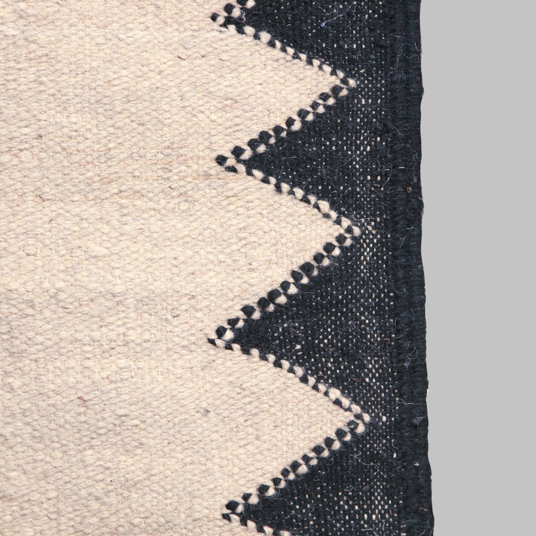 dettaglio del lato di un tappeto marocchino zanafi a tessitura piatta per mostrare la cornice realizzata con triangoli neri affiancati