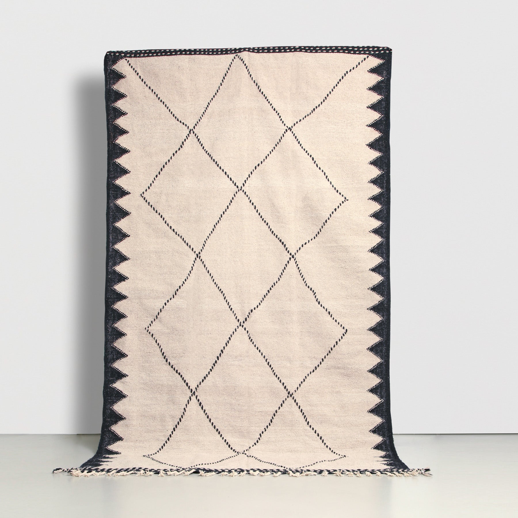 tappeto marocchino zanafi a tessitura piatta realizzato a mano in lana grigia con bordi a zig zag neri e motivo geometrico a rombi neri