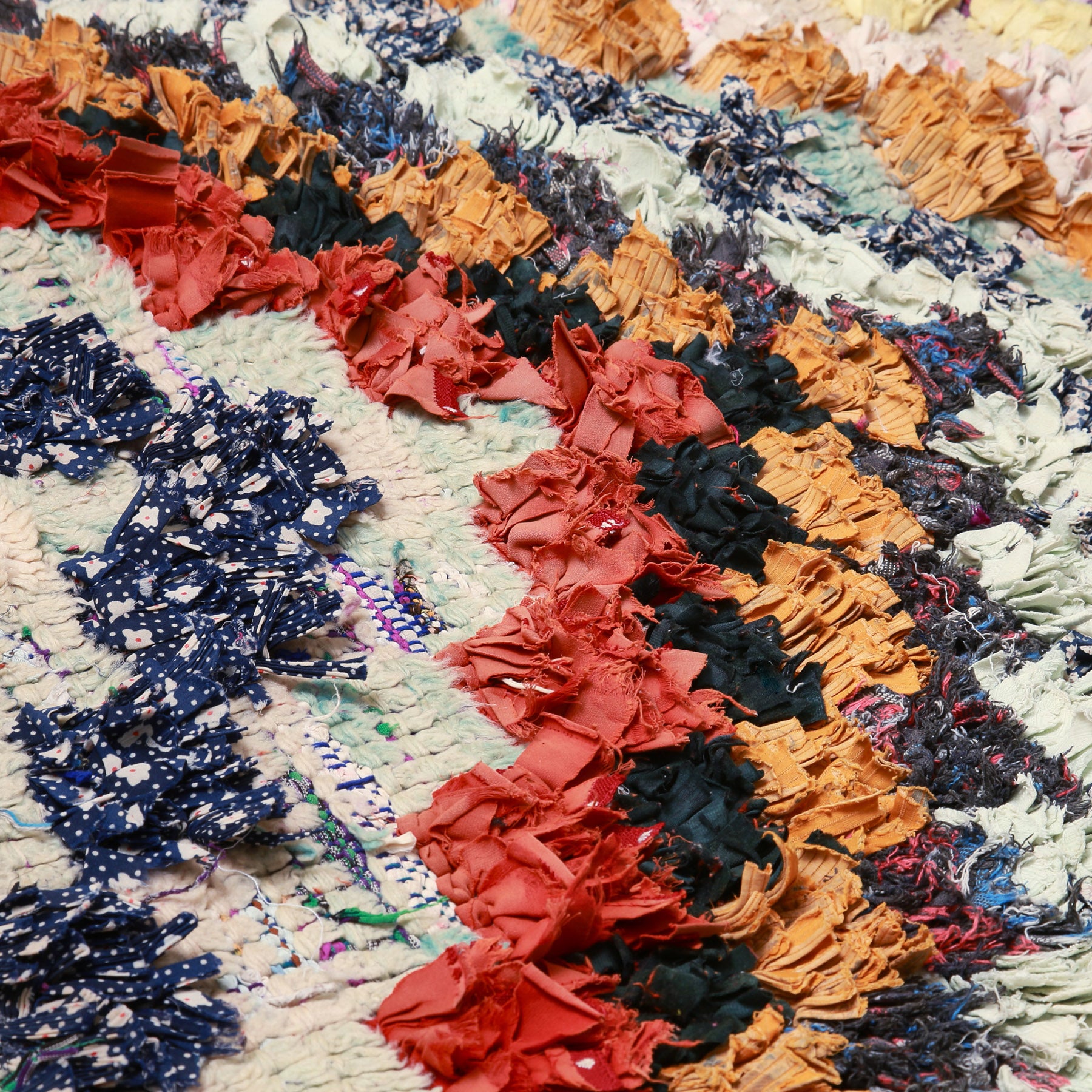 dettaglio dei quadrati colorati realizzati annodando vecchi tessuti e lana a creare delle frecce