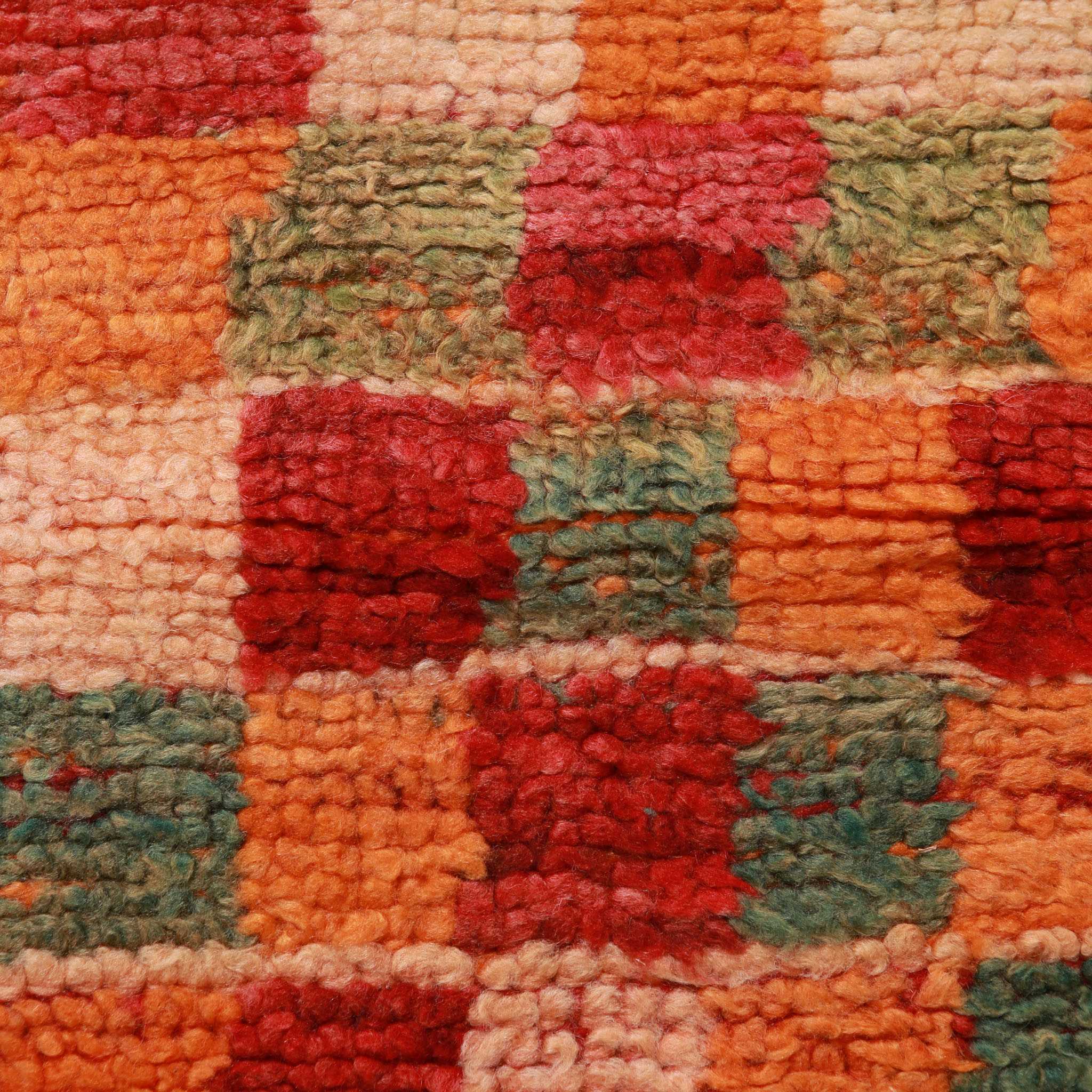 Dettaglio del motivo a quadretti caratteristico del tappeto Boujaad vintage, con texture in lana naturale e alternanza di colori rosso, arancio e verde oliva