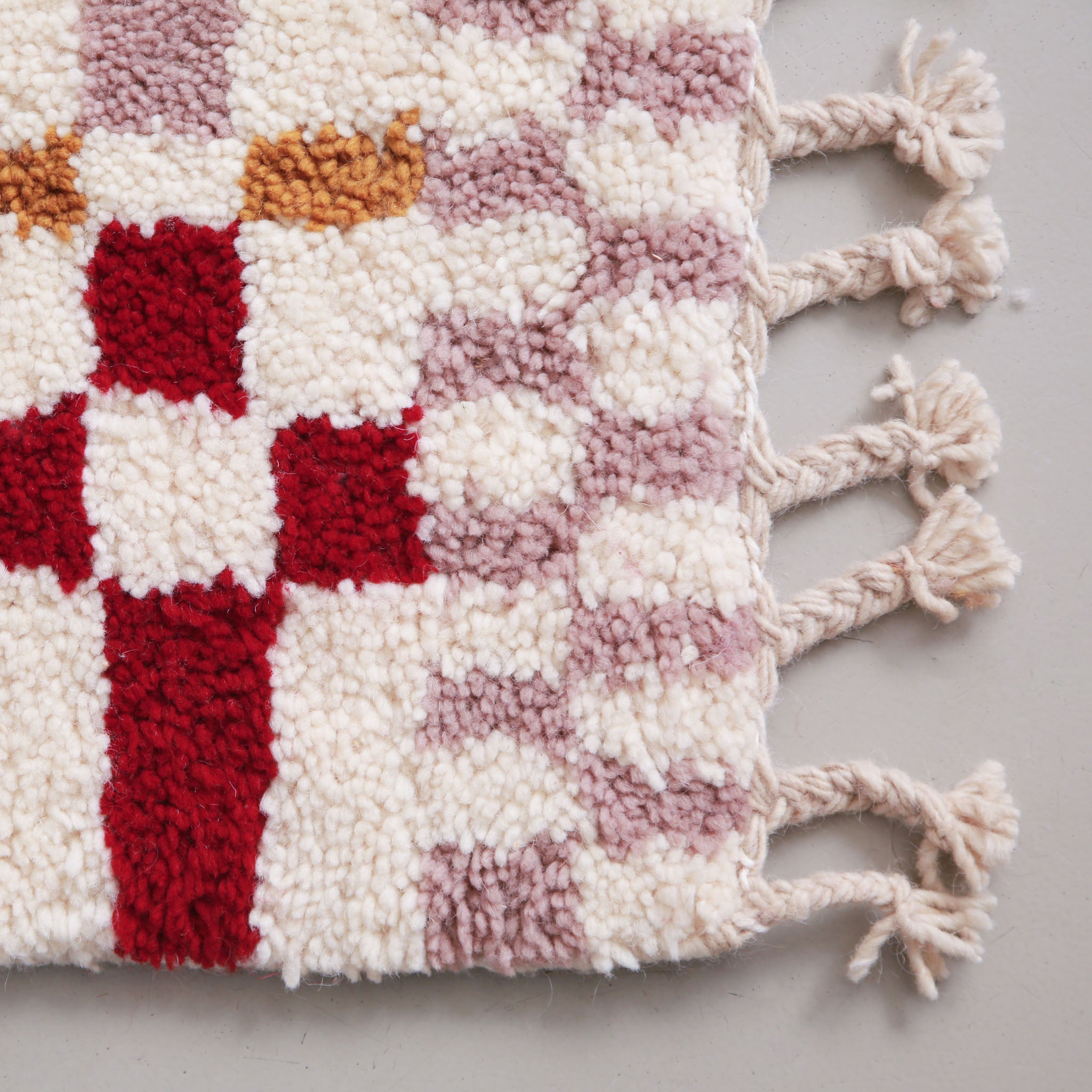 Particolare dei colori e delle frange del tappeto cameretta: rosa malva, rosso, ocra e avorio, annodato a mano