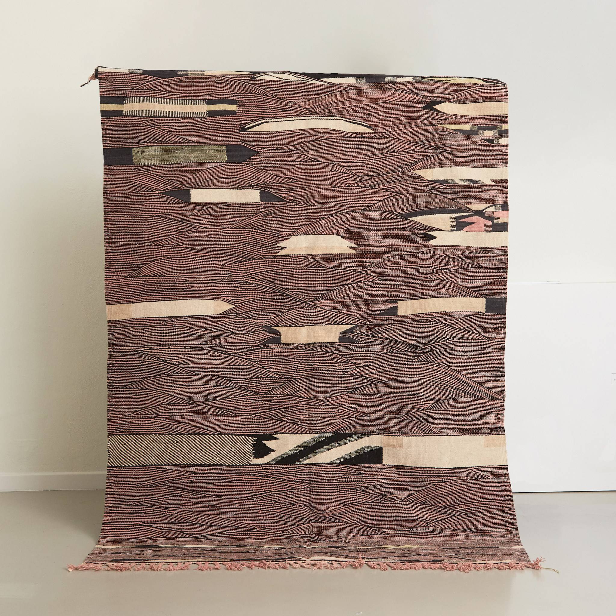 tappeto marocchino kharita a tessitura piatta realizzato intrecciando lana nera e rosa appeso