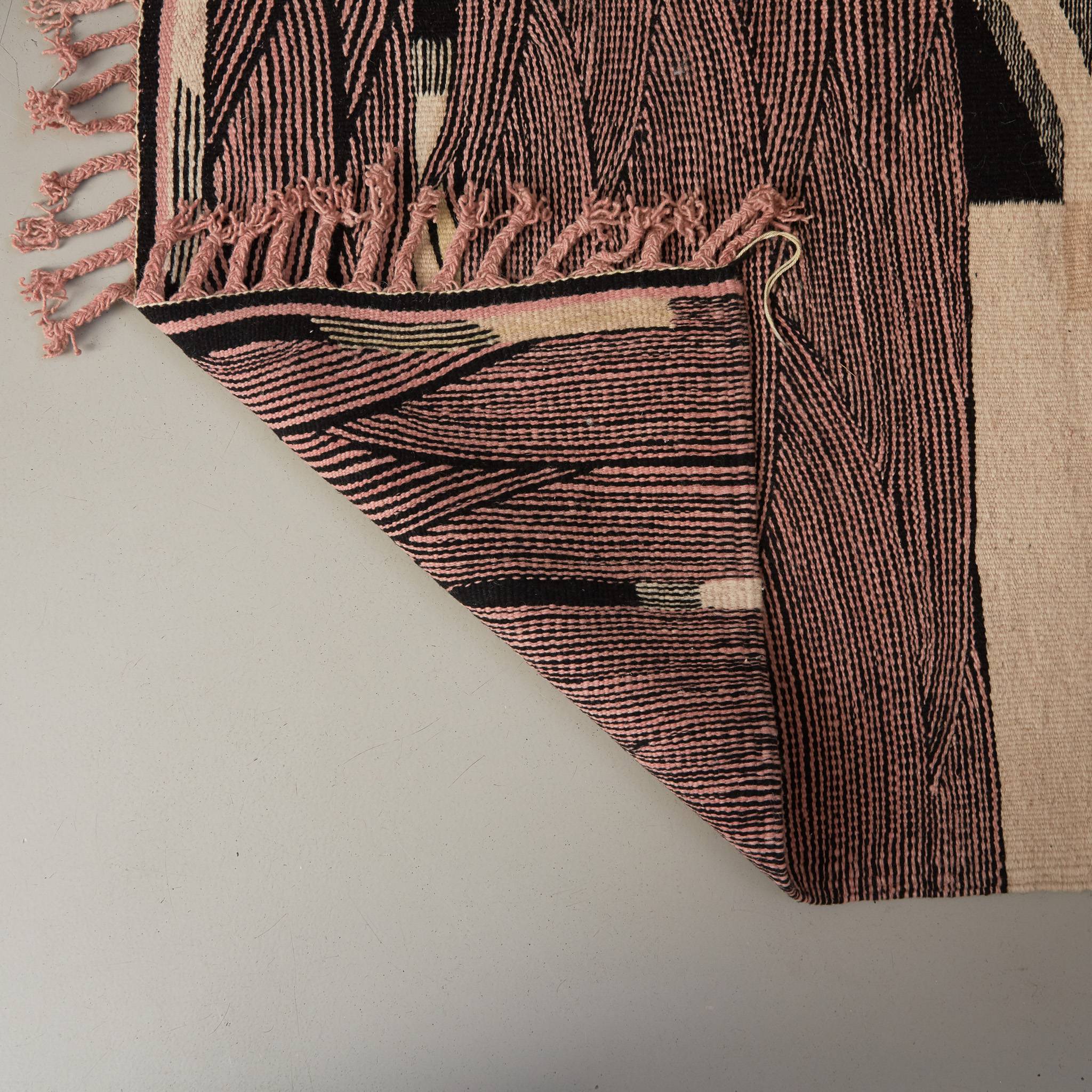 dettaglio del retro di un tappeto kharita a tessitura piatta realizzando intrecciando lana nera e rosa