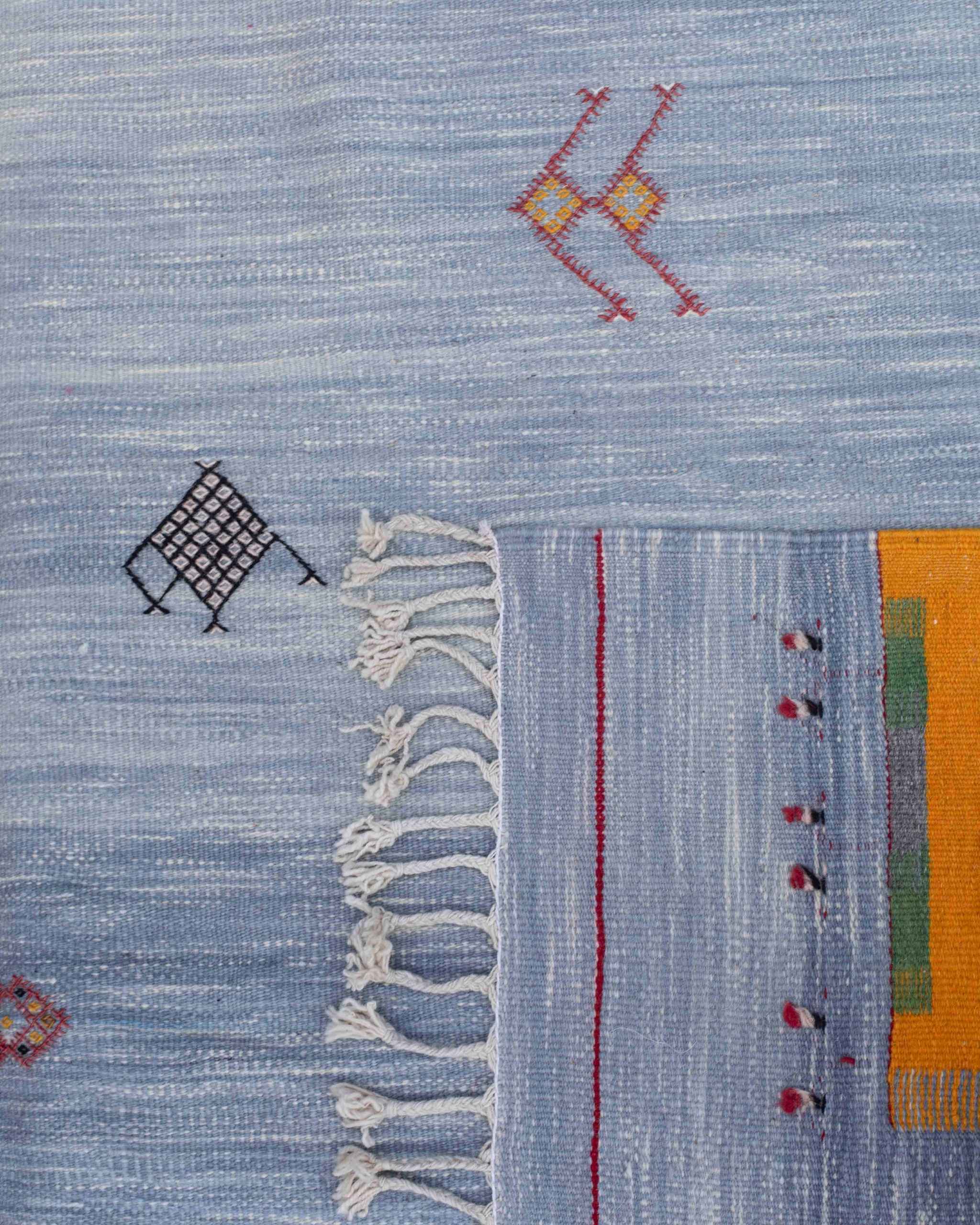 Dettaglio frange, campo e cimosa tappeto Akhnif hanbel/kilim azzurro cielo con piccoli simboli amazigh neri, gialli, rossi, verdi.