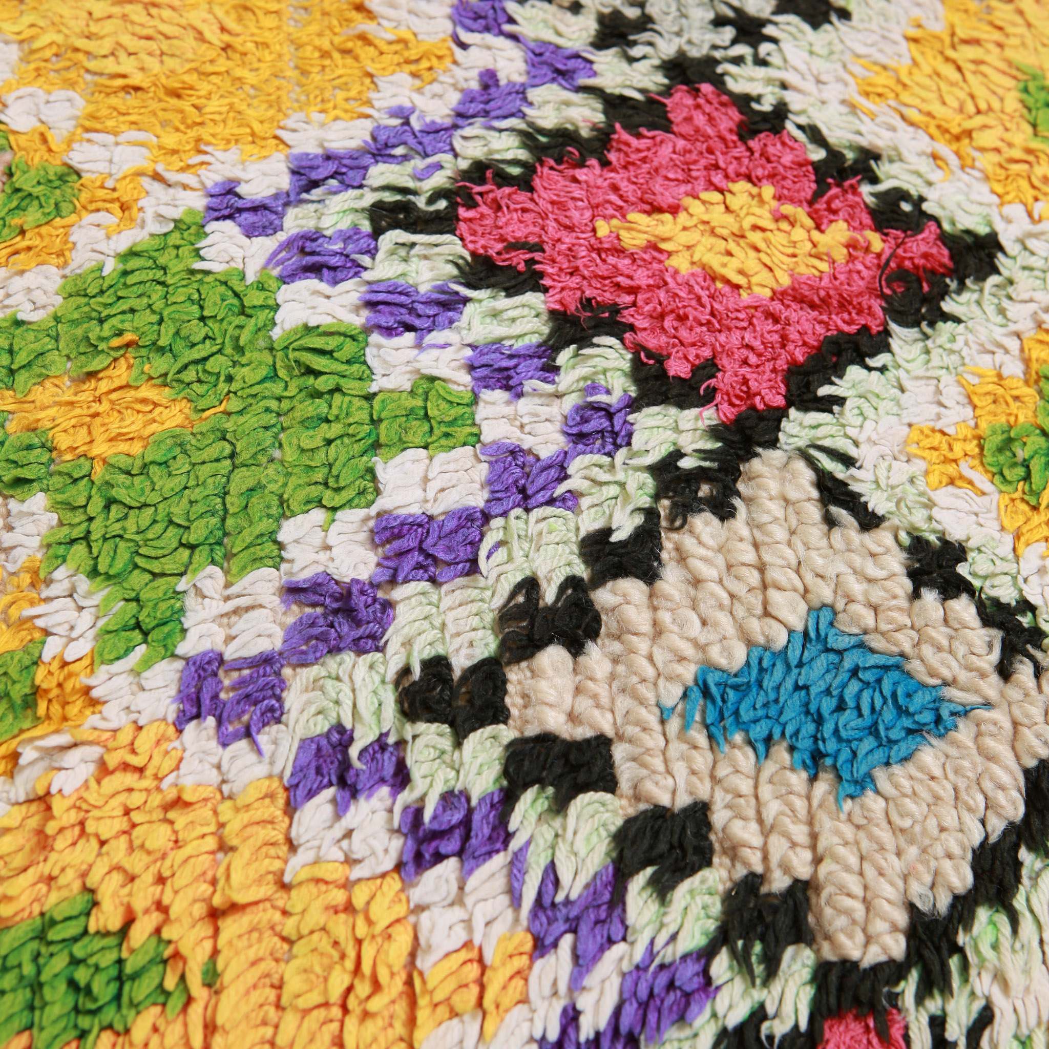 Macro dettaglio della texture in lana del tappeto Marmoucha che mostra la qualità della tessitura e la vivacità dei colori naturali