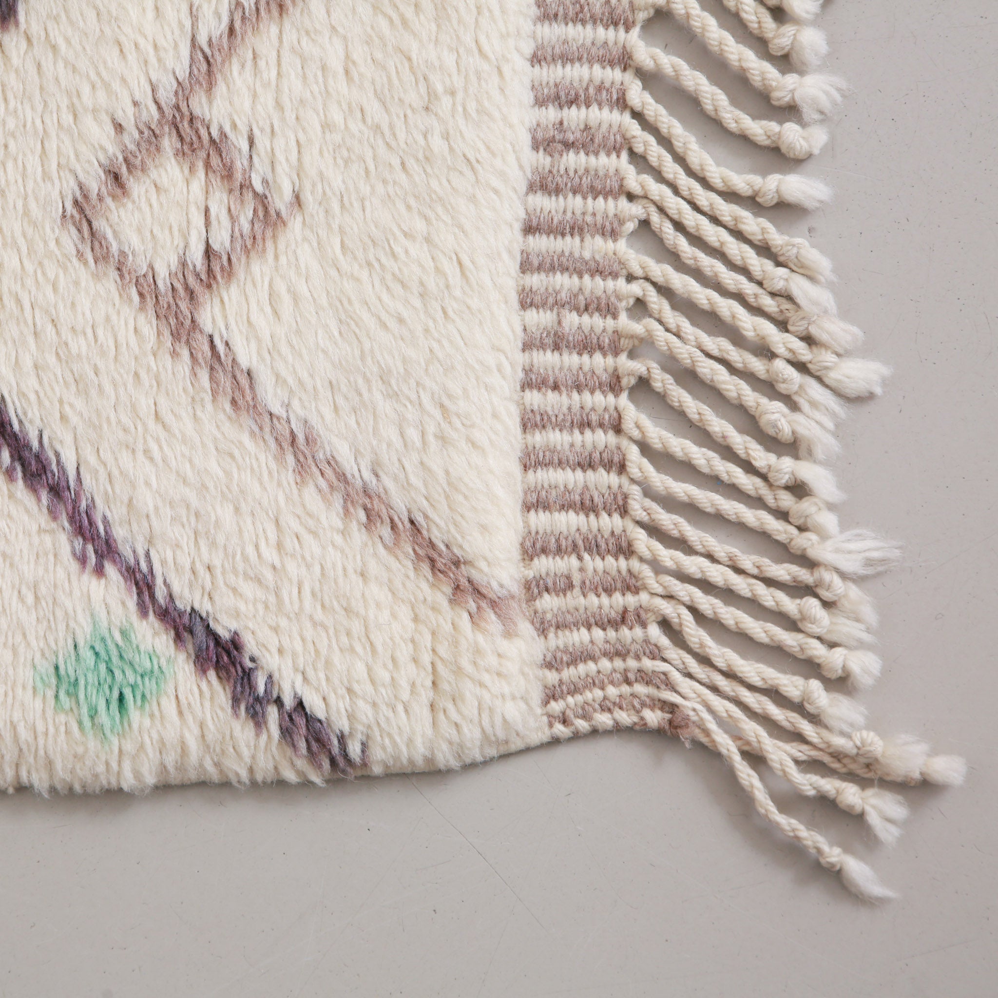 dettaglio dell'angolo di un tappeto beni mrirt in lana beige con linee in lana grigia e nera con frangia beige