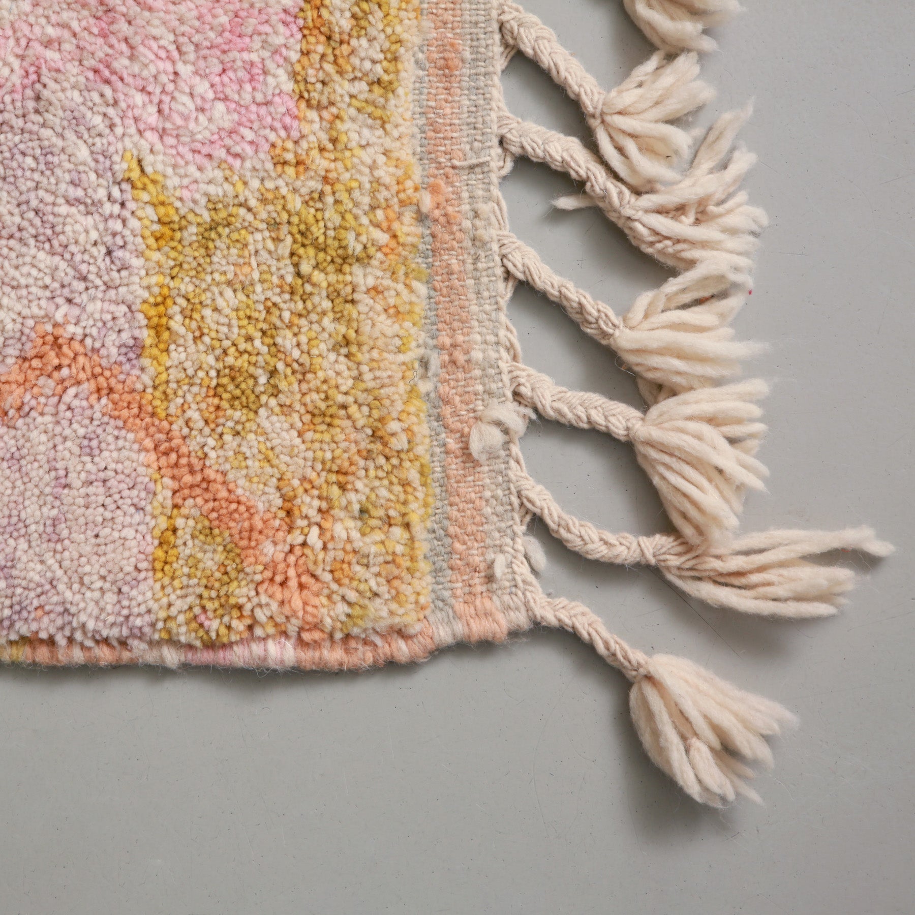 angolo di un tappeto marocchino Beni Ourain con sfumature gi giallo arancione rosa e lilla