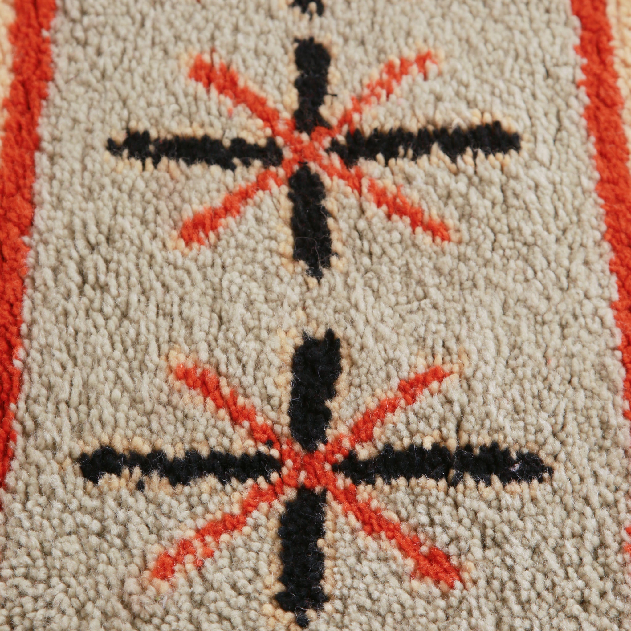 dettaglio di un Tappeto marocchino fatto a mano con motivi geometrici in rosso, beige e crema, caratterizzato da strisce e simboli decorativi come croci e stelle