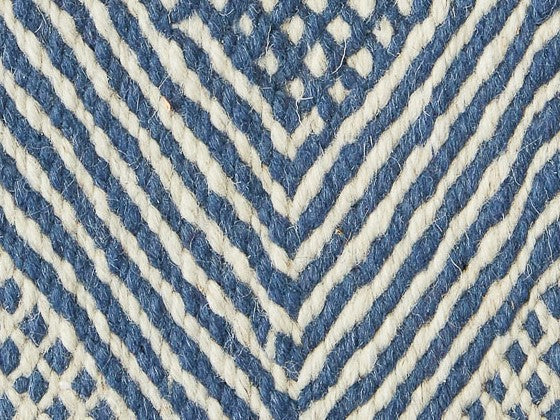 Dettaglio texture tappeto con linee convergenti azzurre e bianche disposte a spina di pesce