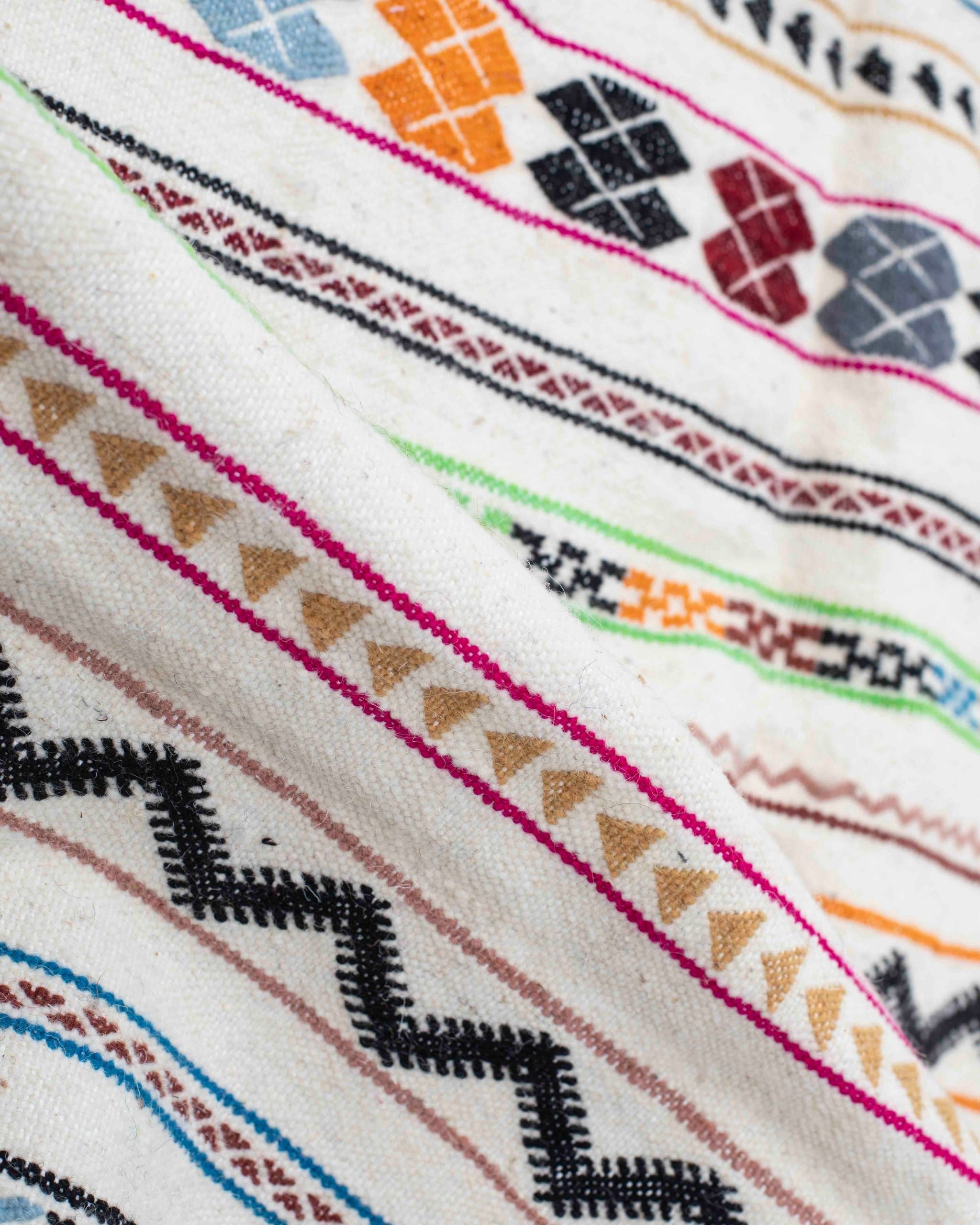 Texture ravvicinata del kilim Zemmour con righe decorate in nero, arancione, verde, azzurro, rosa e bordeaux