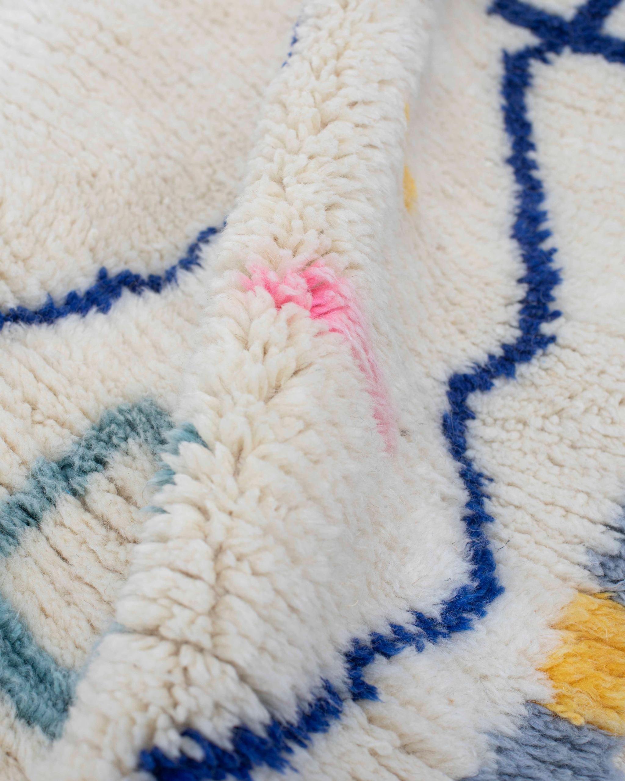 Texture ravvicinata della lana bianca con linea zigzag blu navy del tappeto berbero Azilal annodato a mano