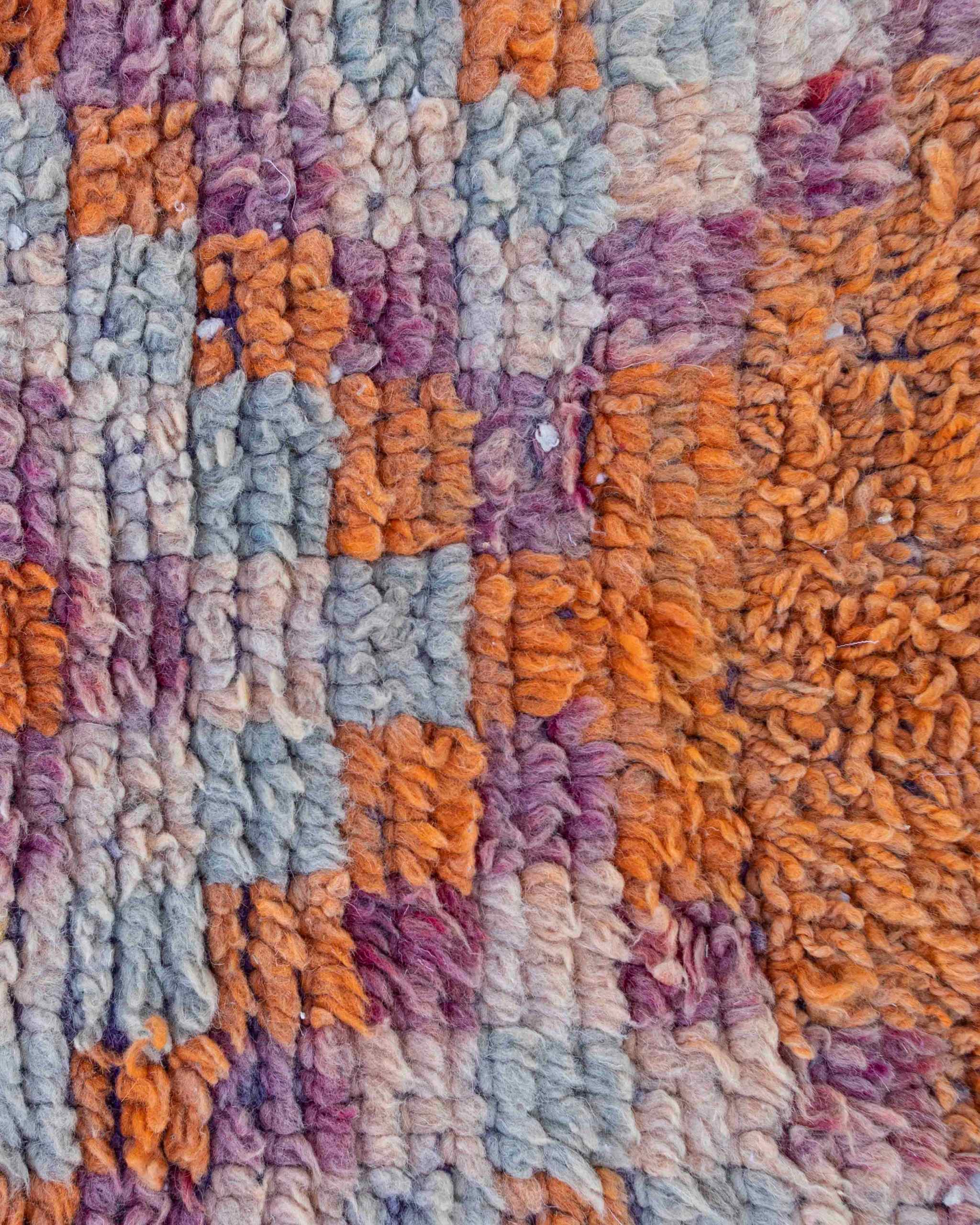 Texture ravvicinata della lana del tappetino Boujaad vintage con sfumature arancioni, lilla, celesti e rosa