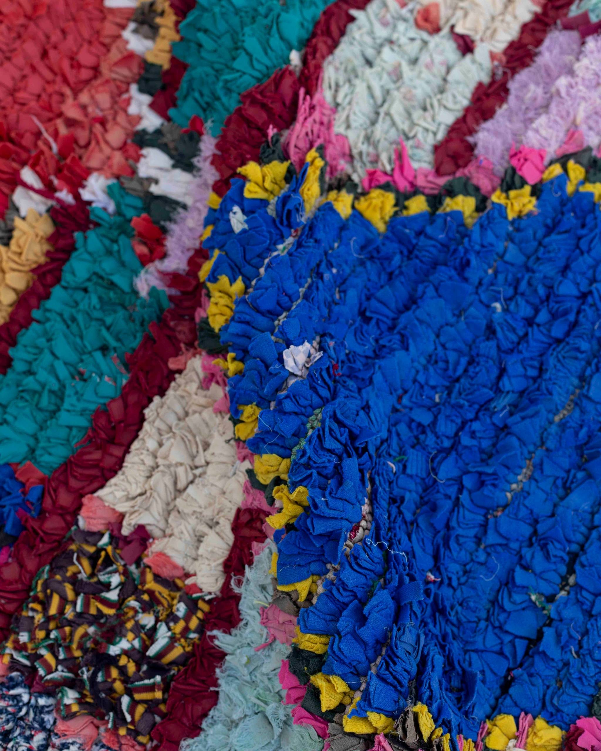Texture ravvicinata del Boucherouite in tessuti riciclati nei toni del blu elettrico, verde ottanio, rosso, giallo e bordeaux