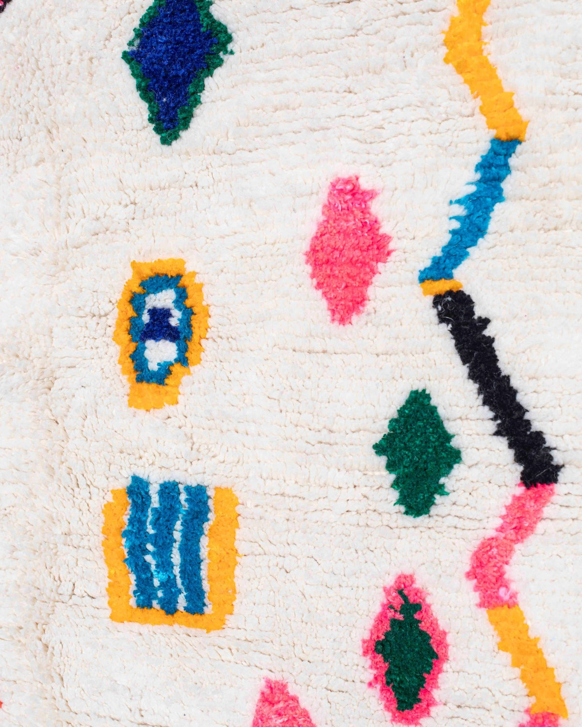 Dettaglio di zigzag, rombi verdi, rosa e blu su fondo bianco del tappeto berbero Azilal