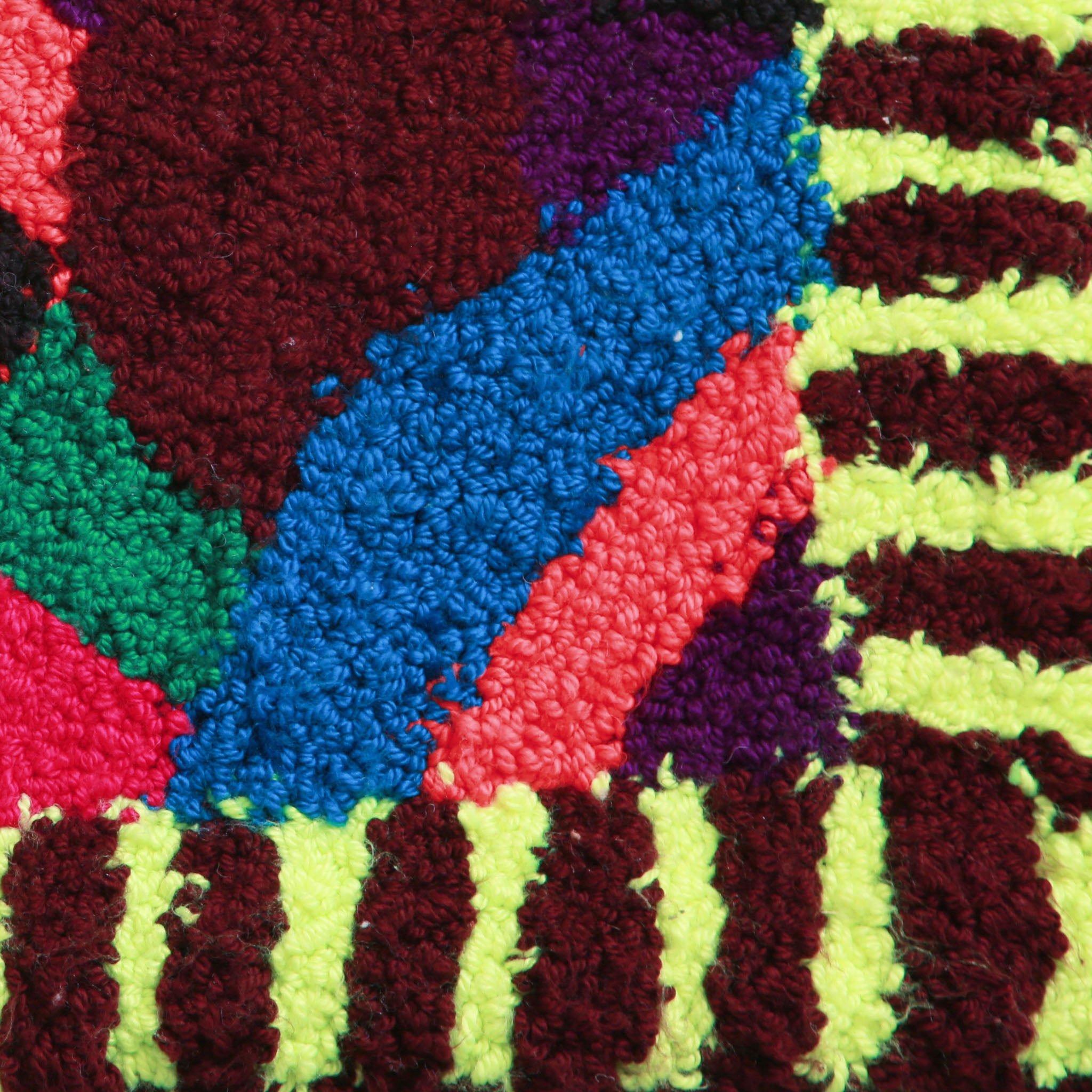 angolo di un tappeto zindekh con cornice a righe gialle e marroni e interno viola rosa blu verde