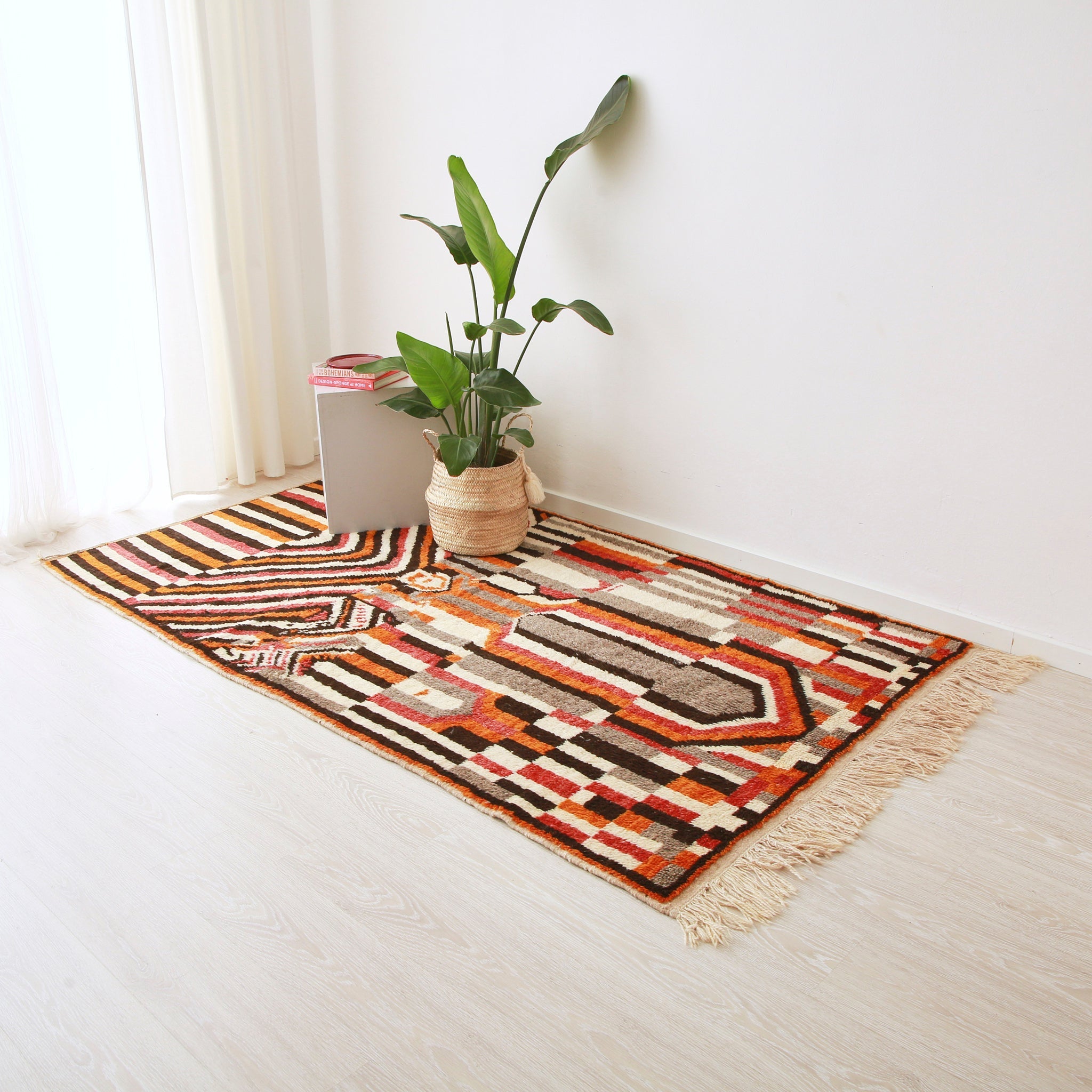 tappeto stile azilal con disegni geometrici che creano una fitta trama di forme dal colore nero, rosso, arancione bianco e grigio disteso sul pavimento