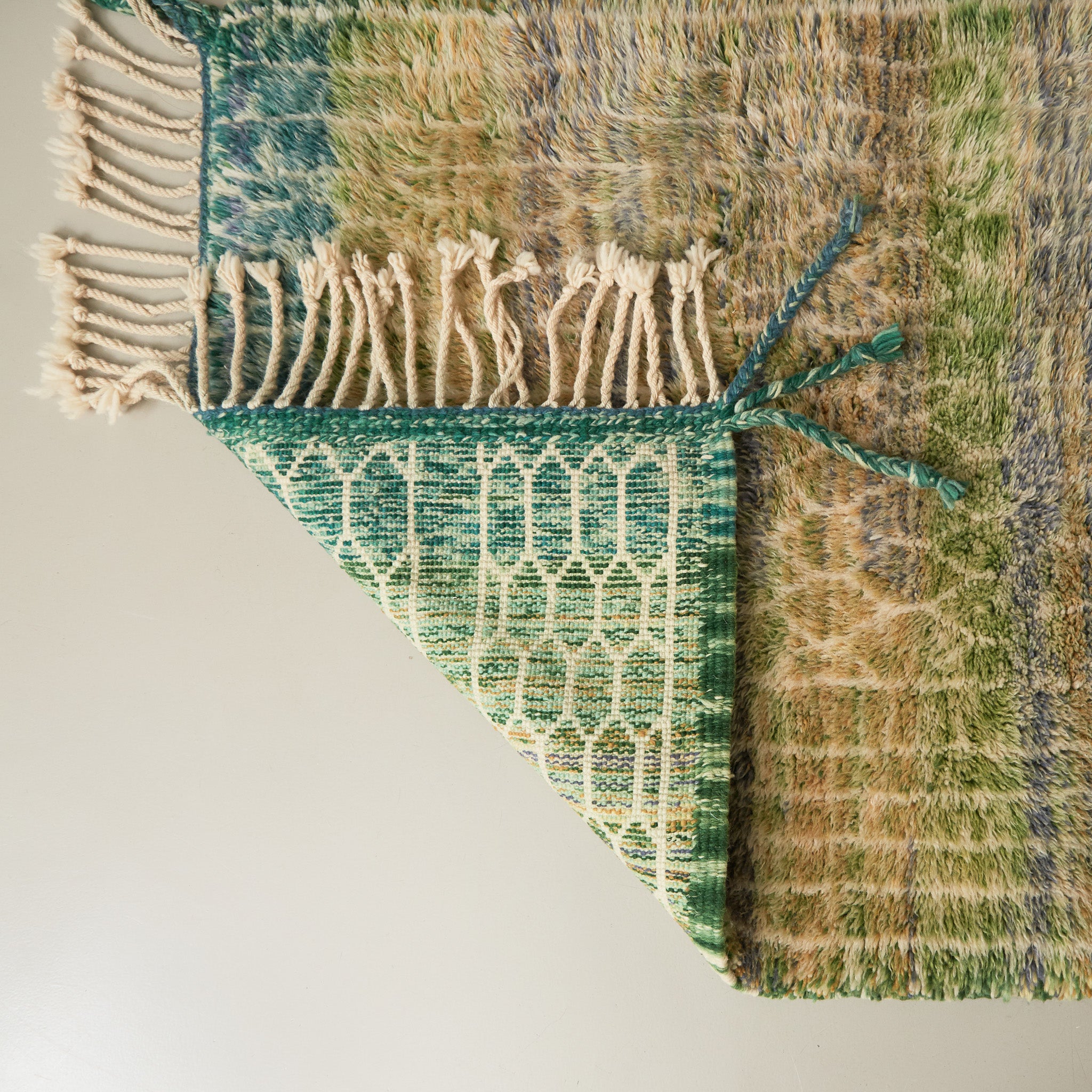 dettaglio della lavorazione di un tappeto beni mrirt per ammirare i nodi ravvicinati di diverse gradazioni di verde