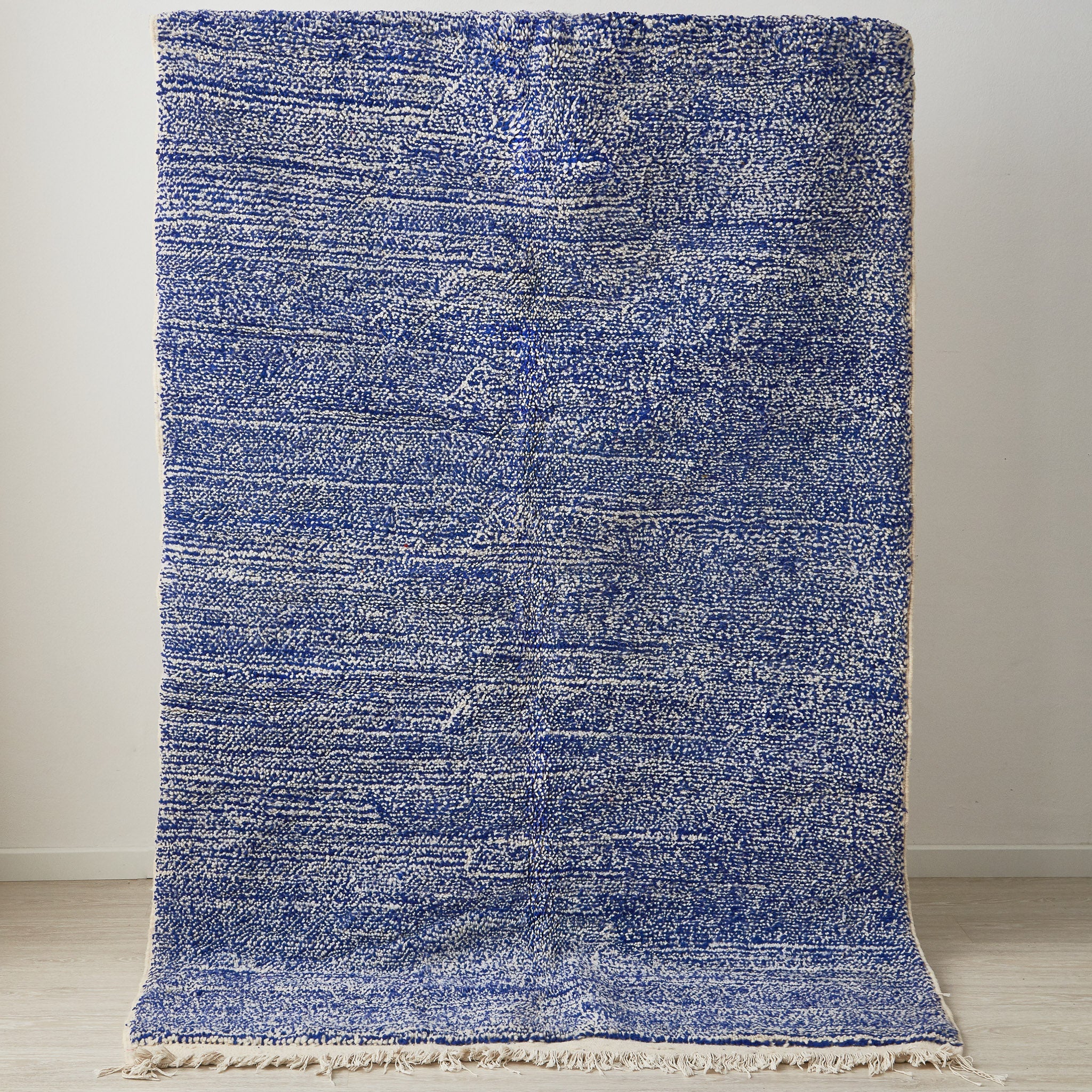 tappeto beni ourain a tinta unita con colore blu melange e frange bianche posizionato in verticale