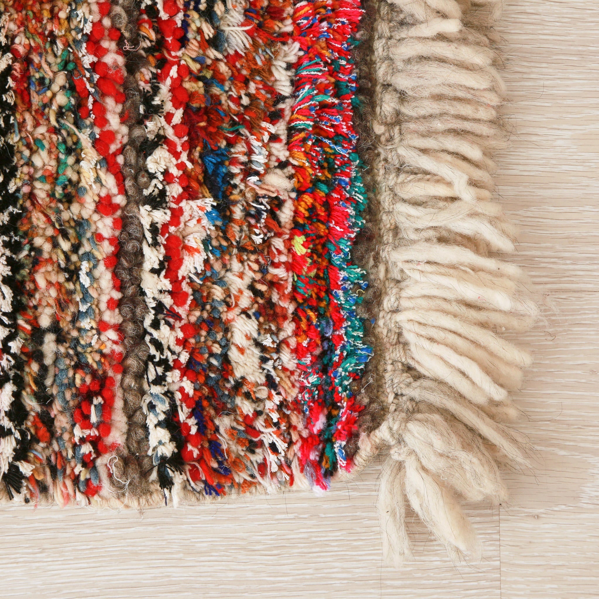 angolo di un piccolo tappeto marocchino realizzato con resti di lana e filati colorati