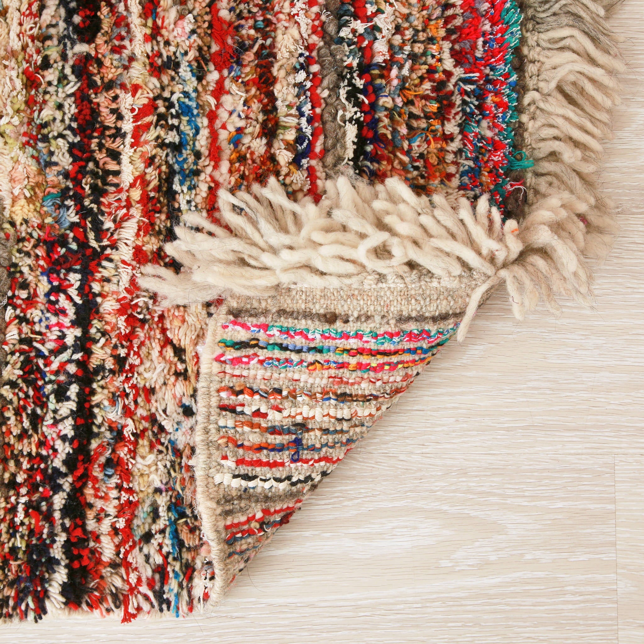 retro di un piccolo tappeto marocchino realizzato con resti di lana e filati colorati