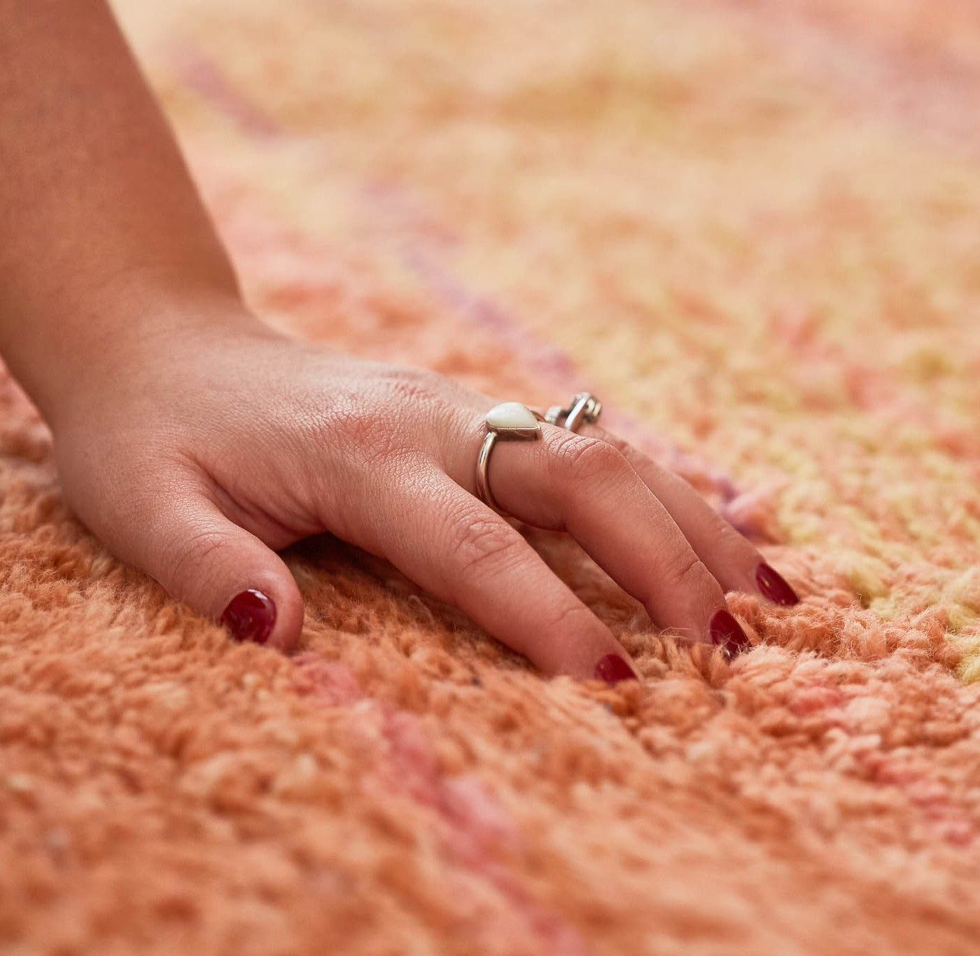 dettaglio di una mano femminile appoggiata su un morbido tappeto