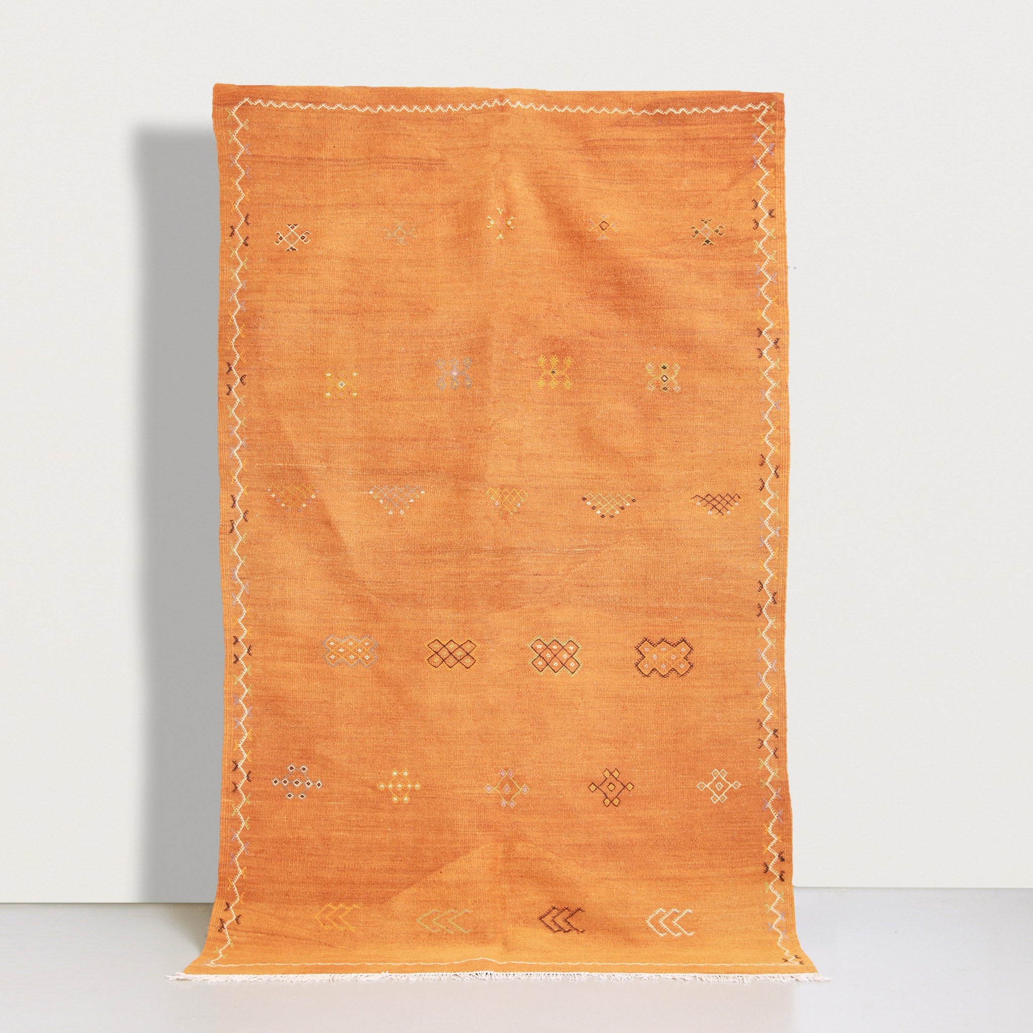 Full view of authentic Akhnif Moroccan rug 247x150cm in orange terracotta with traditional Berber geometric patterns, handwoven flat-weave kilim carpet from Taznakht region with white fringes