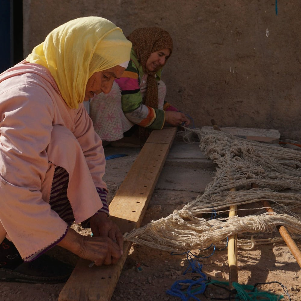 Artisanes marocaines préparant un métier à tisser traditionnel pour le tissage de tapis fait main, illustrant un savoir-faire authentique