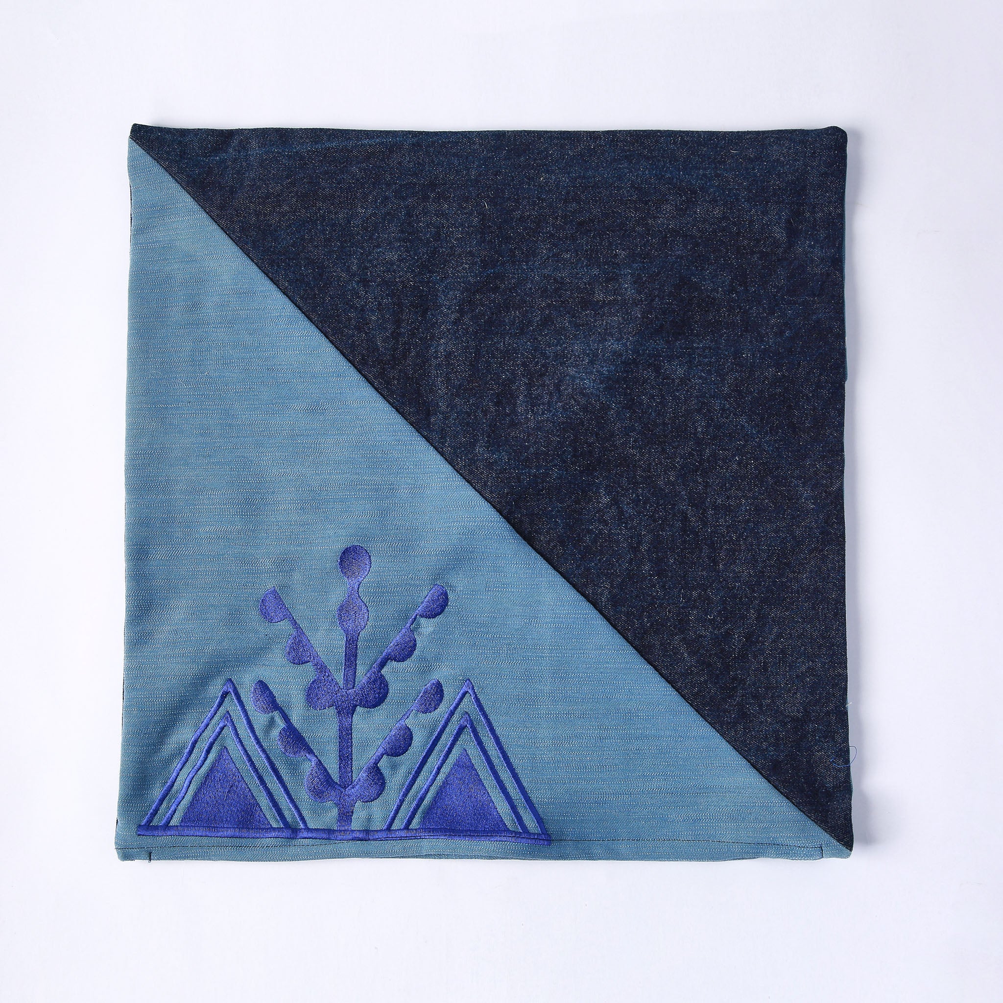 cuscino quadrato realizzato con tessuti in jeans di due colori e ricamo viola del simbolo amazigh dell'ulivo