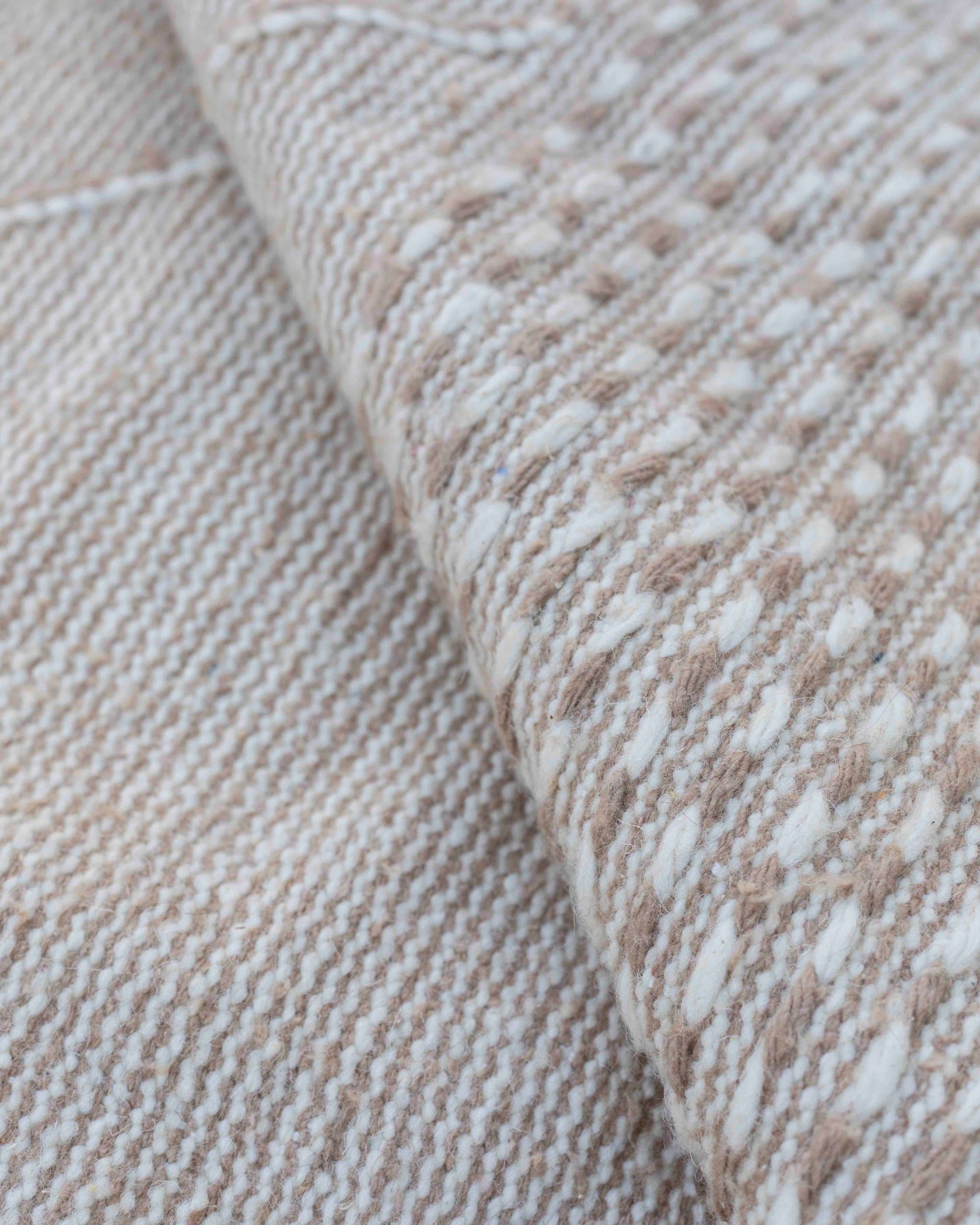 Dettaglio del decoro a righe e cordine tono su tono del tappeto Hanbel in lana beige e avorio