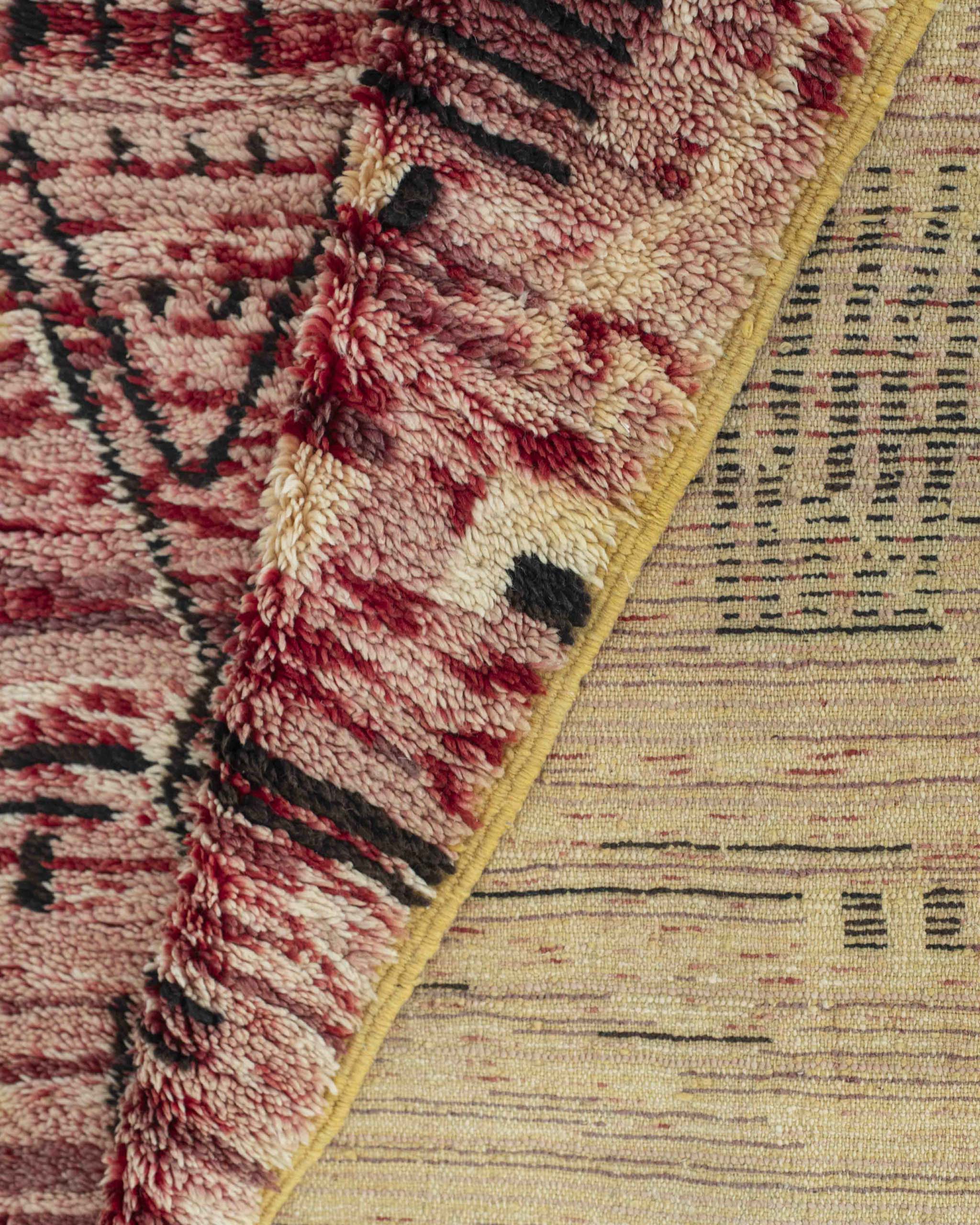 Dettaglio del tappeto in lana a pelo corto rosa-rossa-bianca-nera e retro con trama a vista, bordo annodato