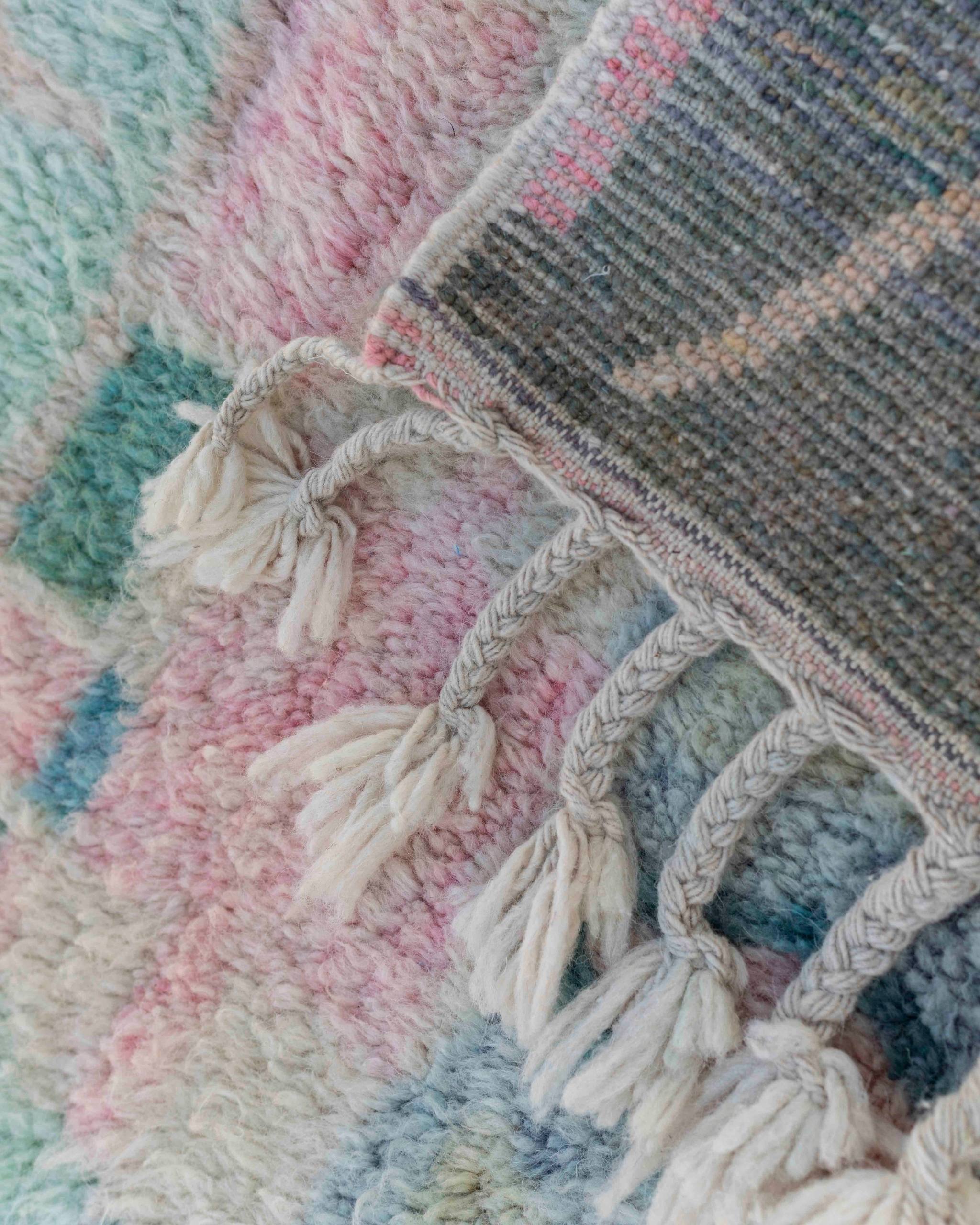 Dettaglio delle frange intrecciate e del retro di un tappeto Beni Ourain multicolore in lana in colori pastello delavé
