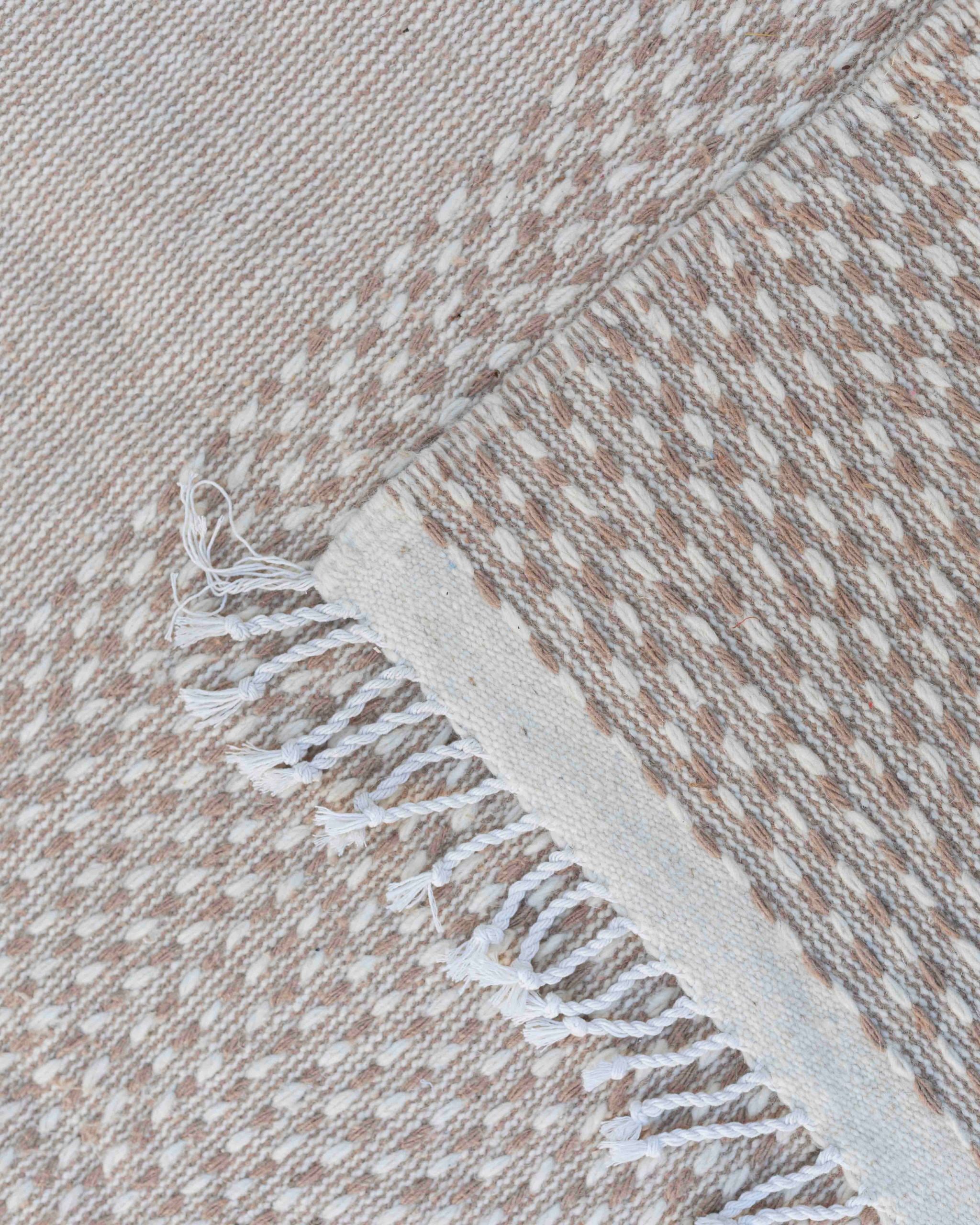 Dettaglio delle frange chiare e della tessitura beige avorio di un tappeto kilim-Hanbel in lana senza pelo
