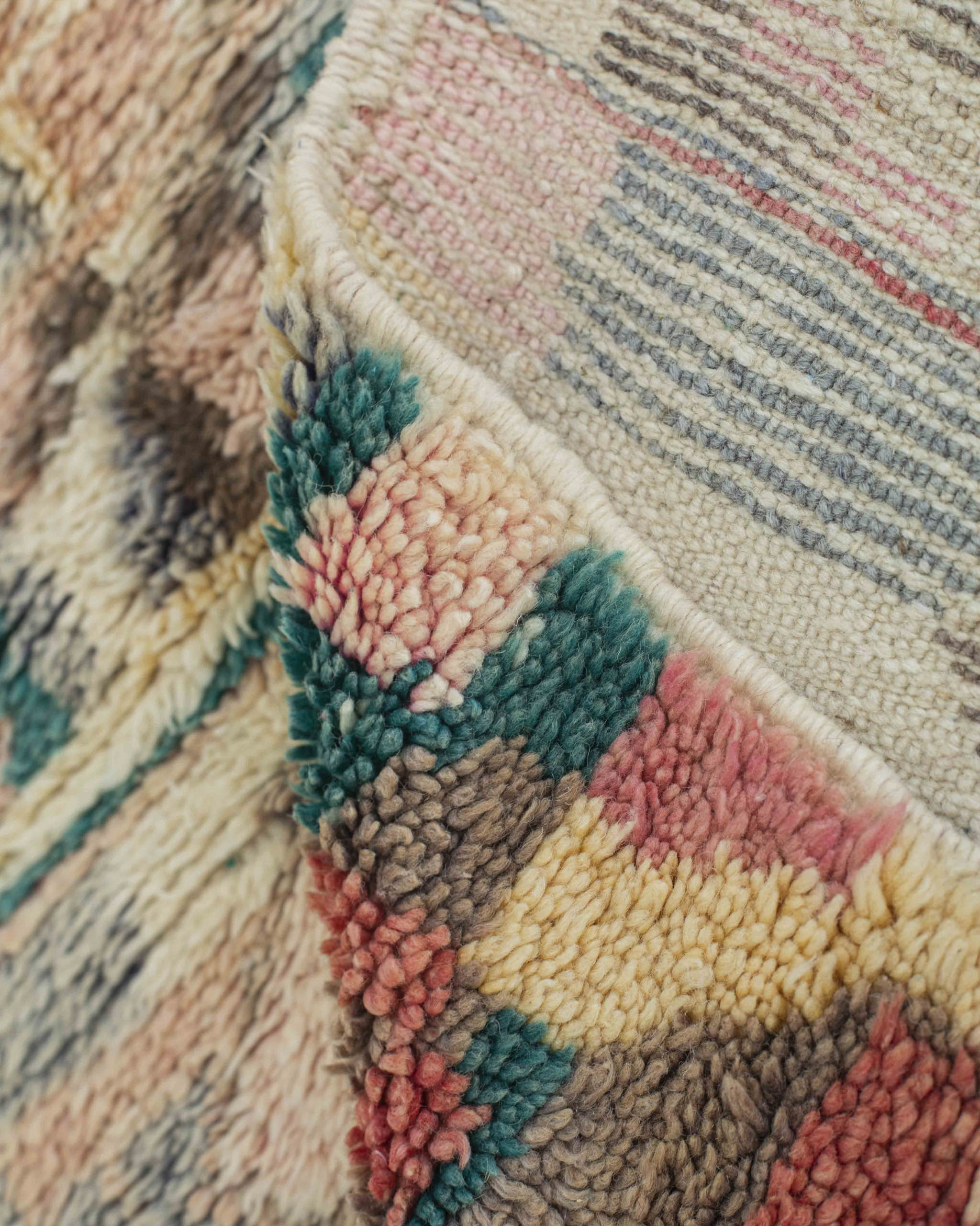 Dettaglio dritto-rovescio del tappeto artigianale con trama a vista e cimosa annodata a mano
