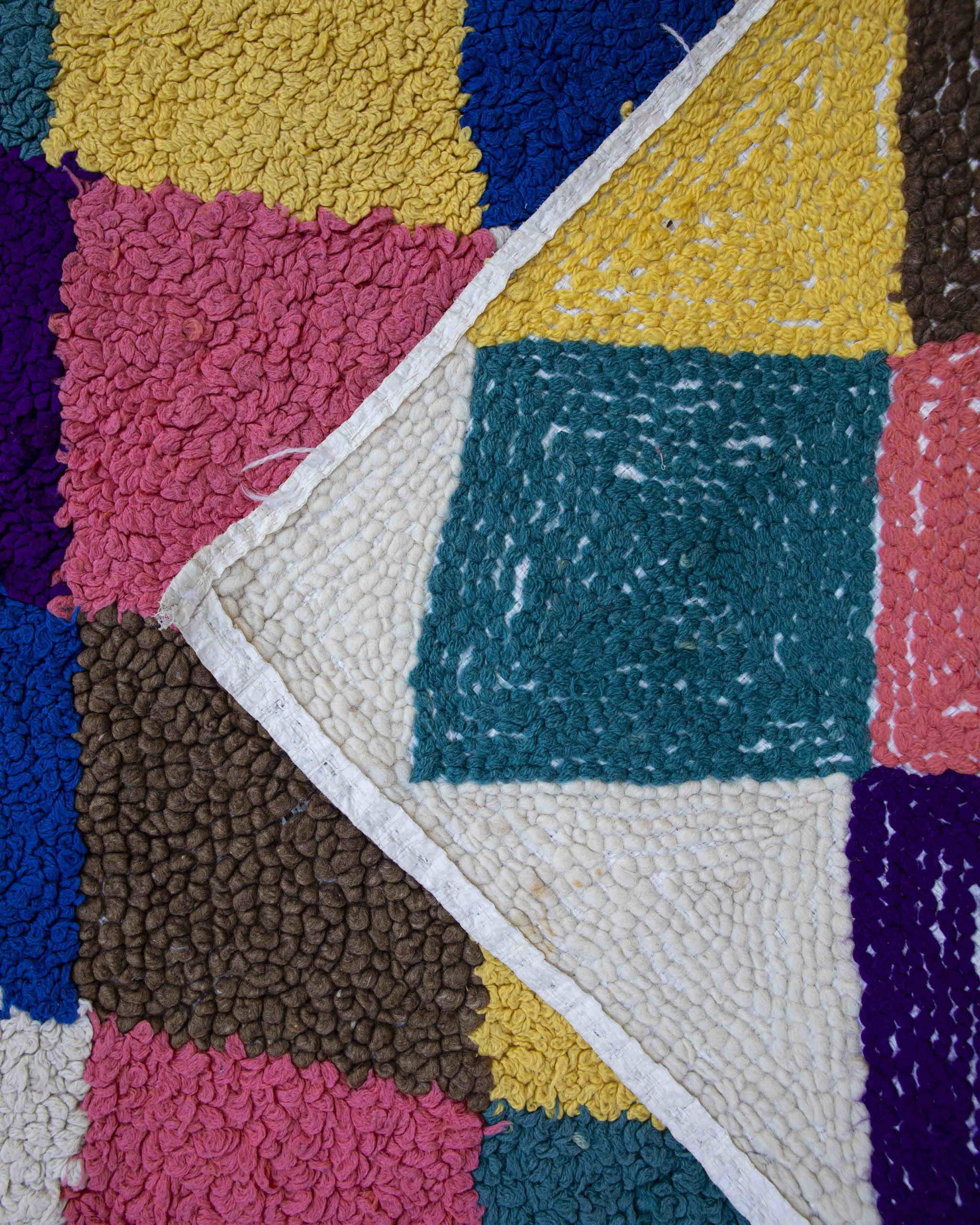 Dettaglio fronte-retro del tappeto passatoia fatto a punch needle con filati colorati su base in plastica riciclata
