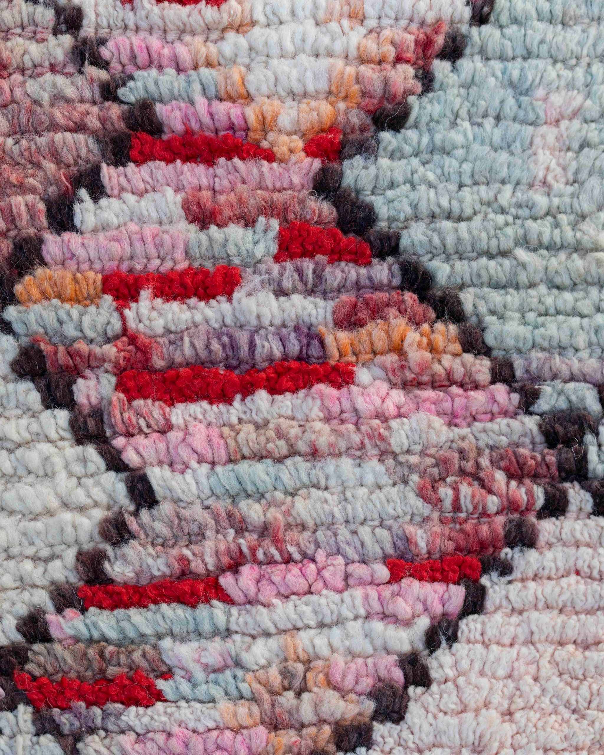 Dettaglio della superficie in lana a pelo corto della passatoia Boujaad in lana rosa, grigio-azzurra, rossa e bianco crema, con rombi concatenati su fondo multicolor 