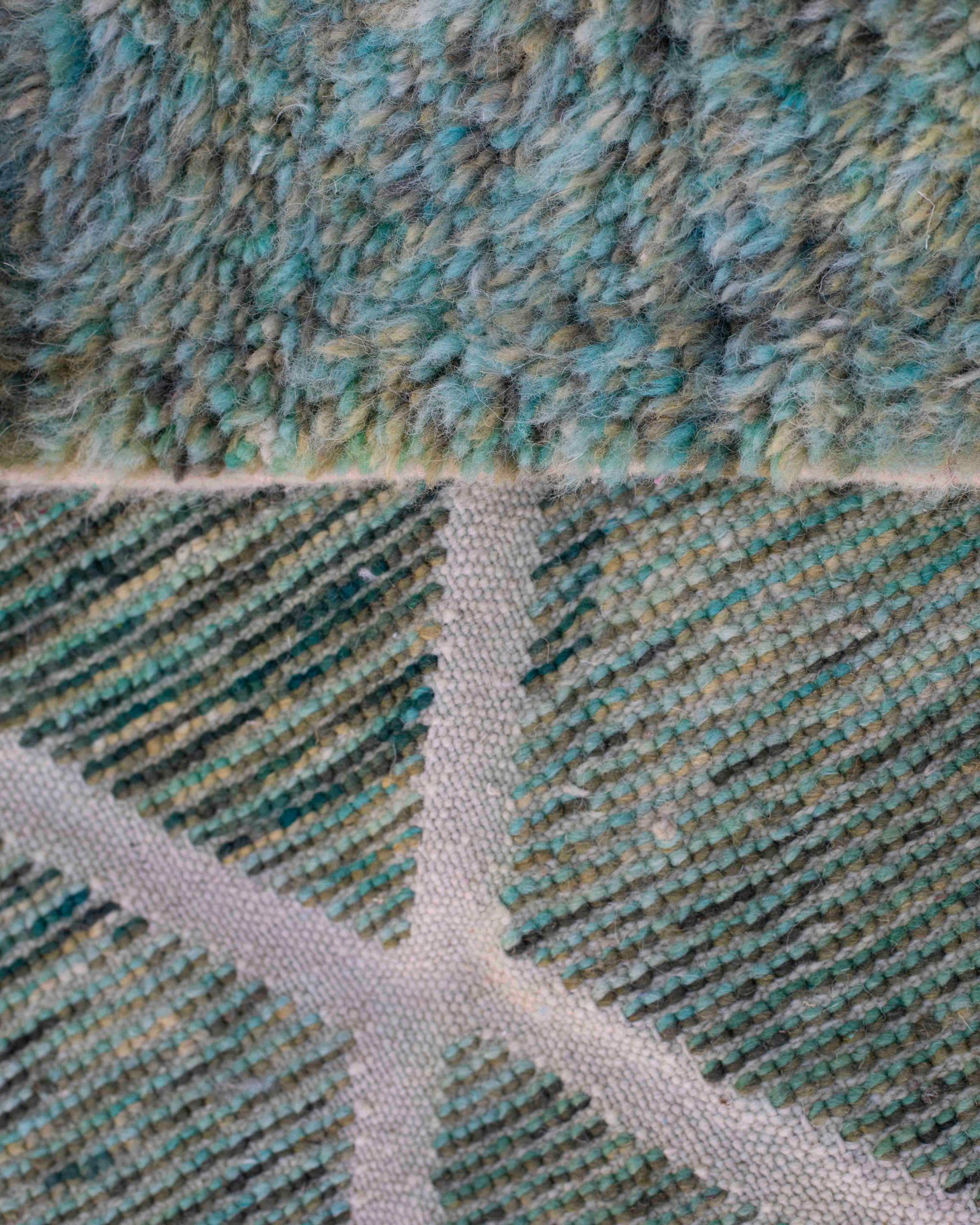 Dettaglio dritto-rovescio del tappeto in lana blu-verde con pattern a rombi e sfumature beige e grigie
