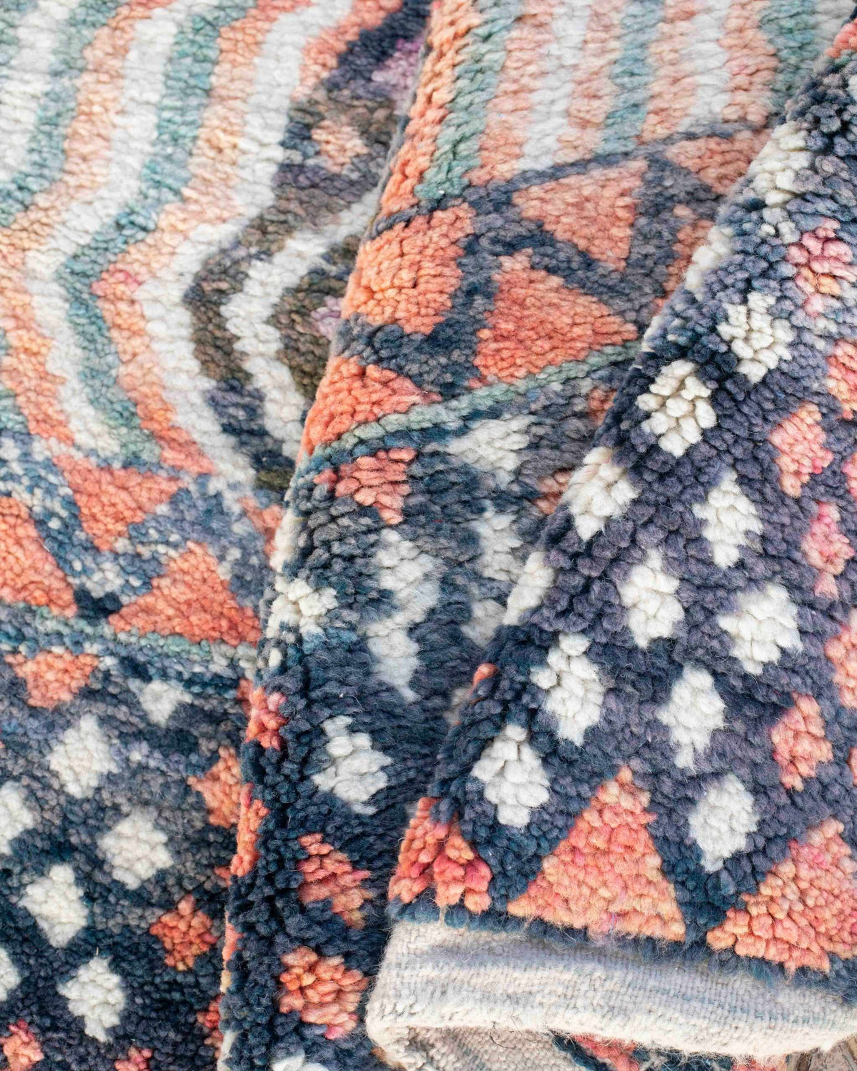 Dettaglio del tappeto in lana piegato con fantasia geometrica a rombi, zigzag e linee ondulate