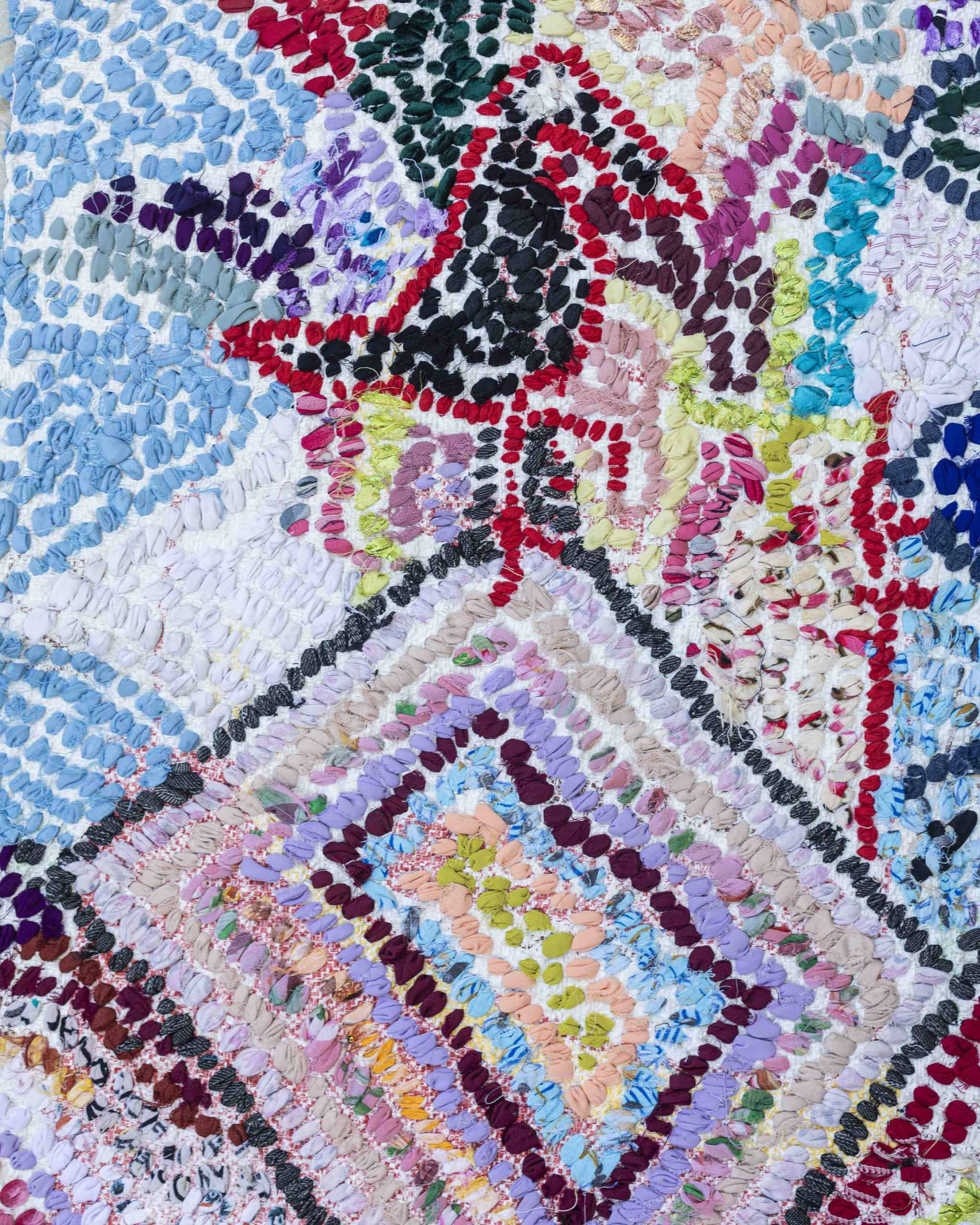 Dettaglio del retro del tappetino con base ricavata da sacchetti in plastica e tessuti annodati a vista