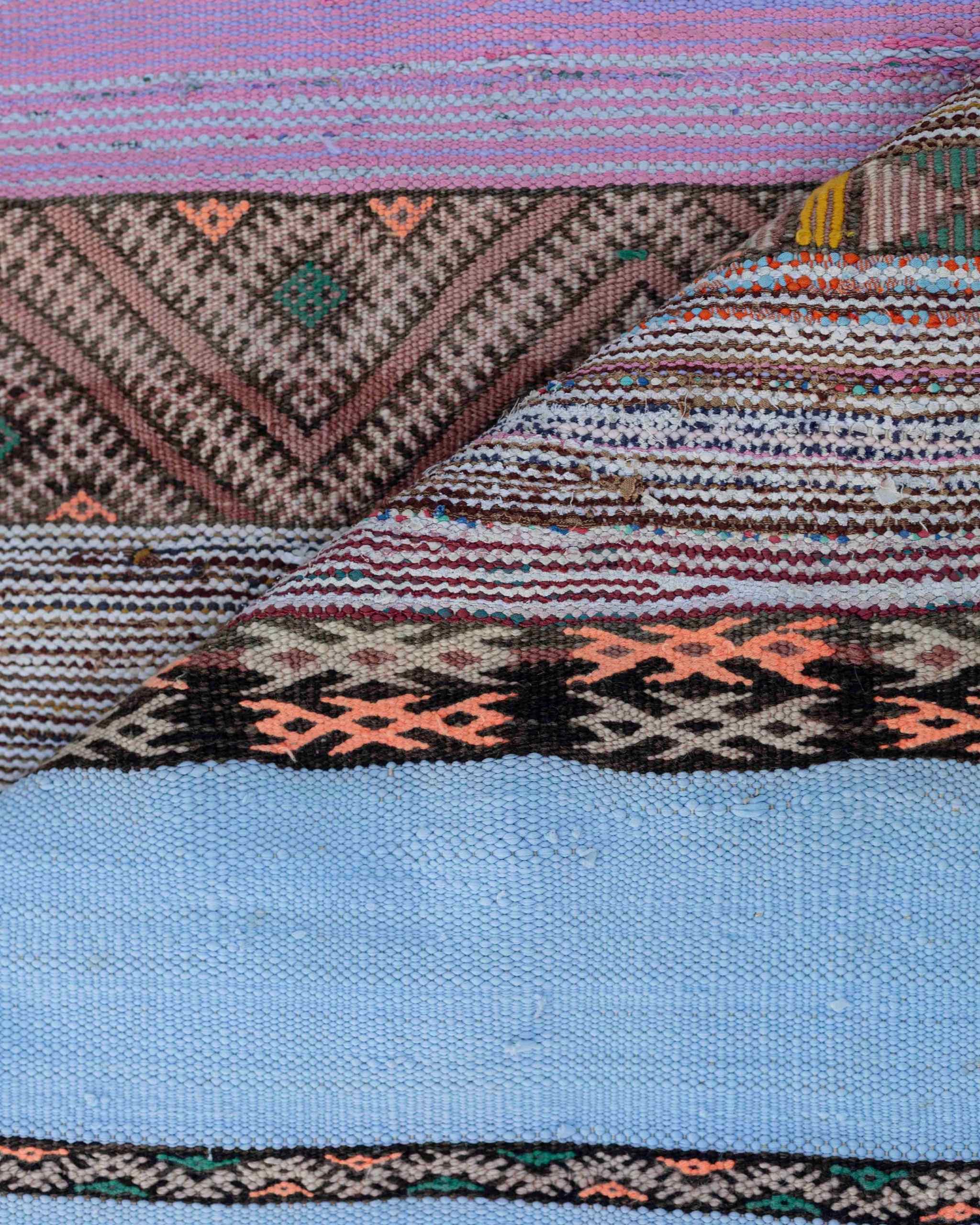 Dettaglio delle righe colorate del tappeto boucherouite boho con fasce tinta unita celeste e rosa e geometrie morroni, verdi, arancioni, nere
